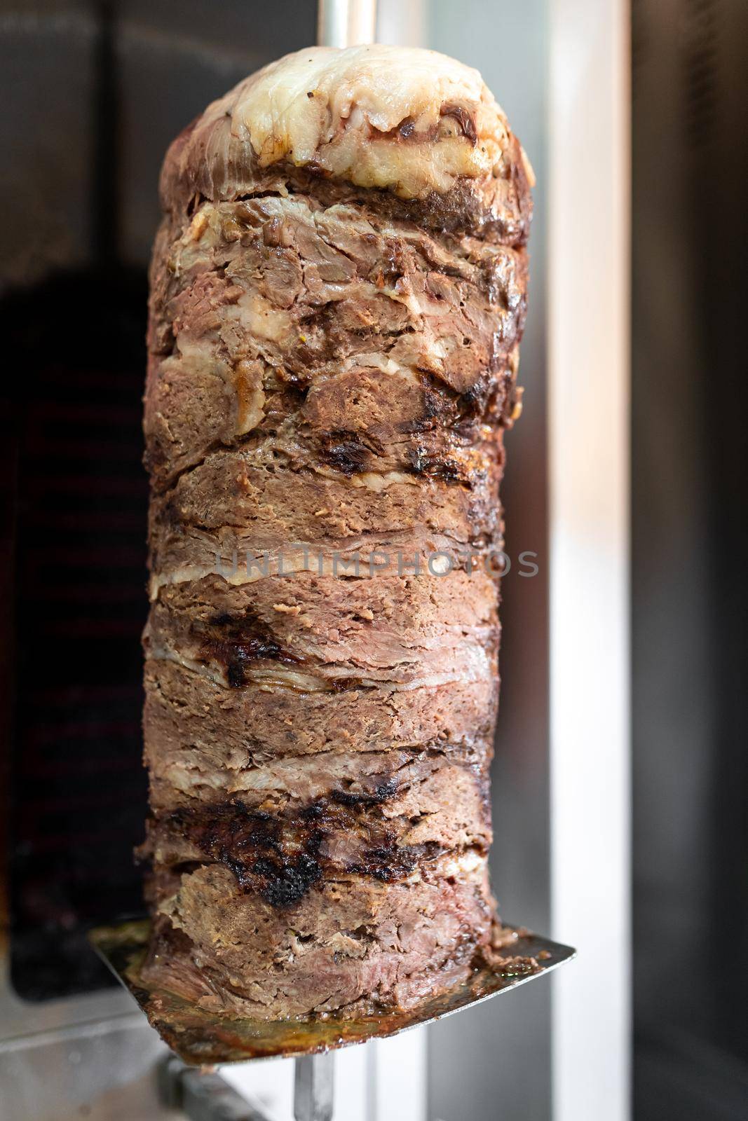 Vertical rotisserie marinated beef meat for Doner Kebab, Turkish street food.