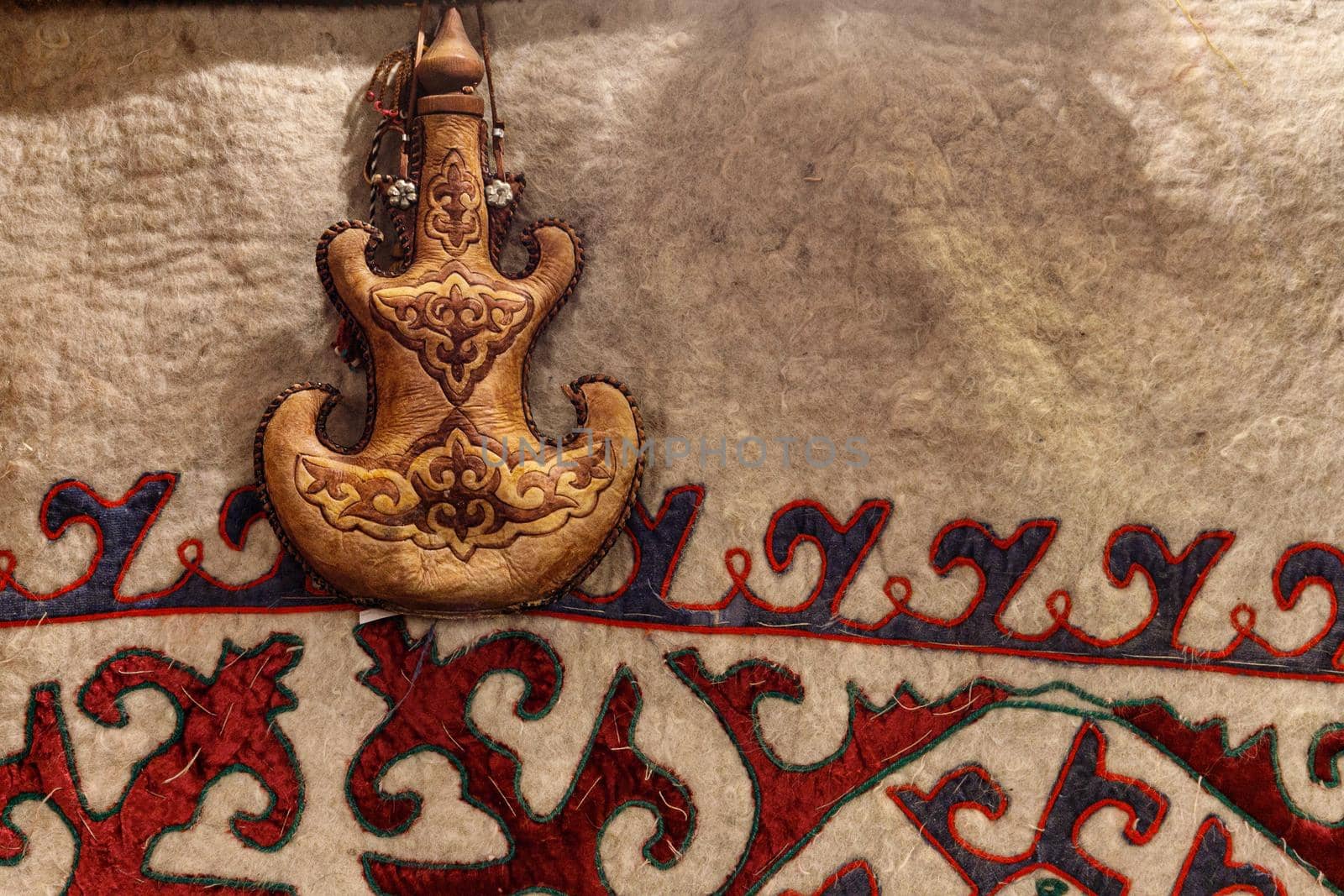 Torsyk - Kazakh national container for drinks with turkish ornament on the background of a carpet with central asian patterns.