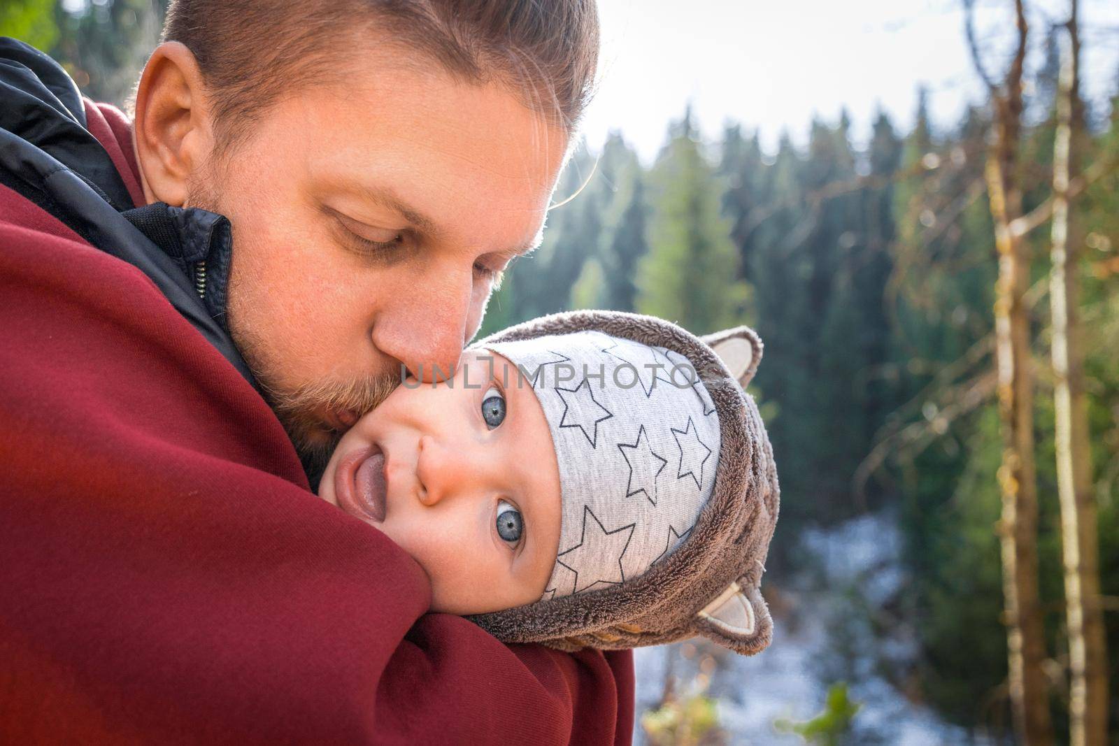 Father kisses his funny baby boy on a walk outdoor.