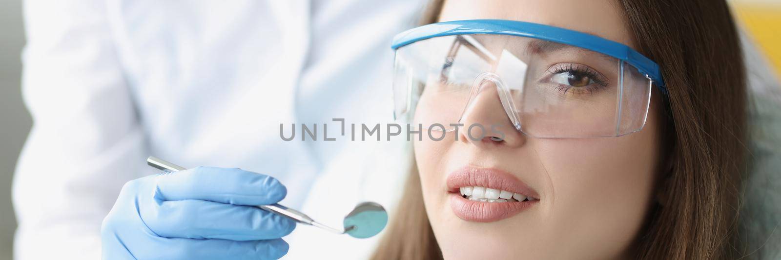 Portrait of pretty woman sitting at dentist chair. Stomatologist holding dental instruments. Dental care, stomatology clinic and healthy teeth concept