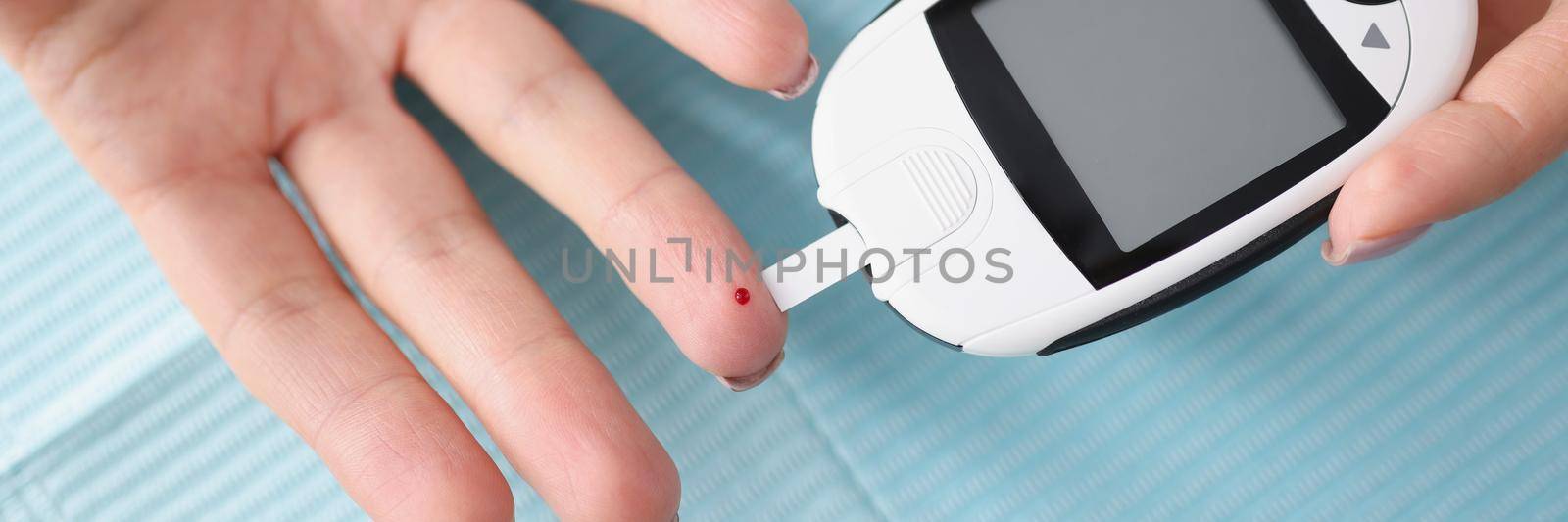 Close-up of female hands holding glucometer with strips. Medical portable device for determining approximate concentration of glucose in blood. Diabetic using glucose meter