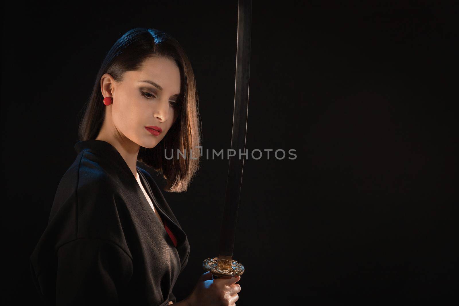 Portrait of a pensive young warrior woman with an Asian sword.