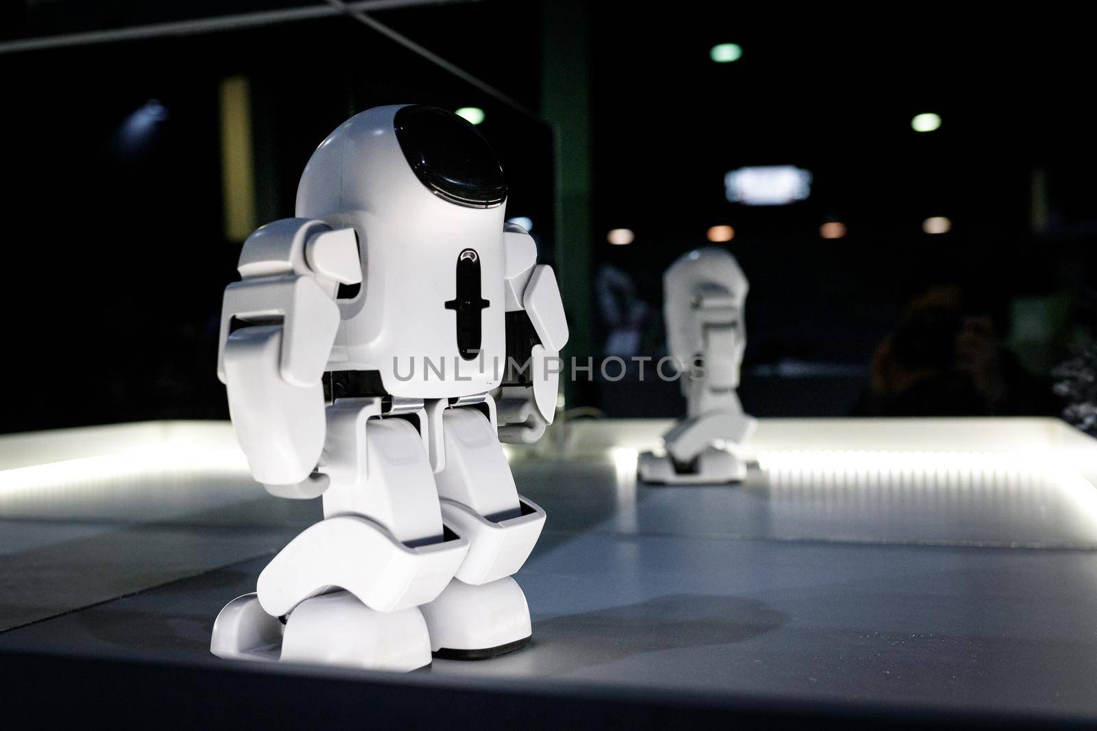 White humanoid robot at the exhibition illuminated stand with mirrors at the robot festival. Almaty, Kazakhstan - February 19, 2022