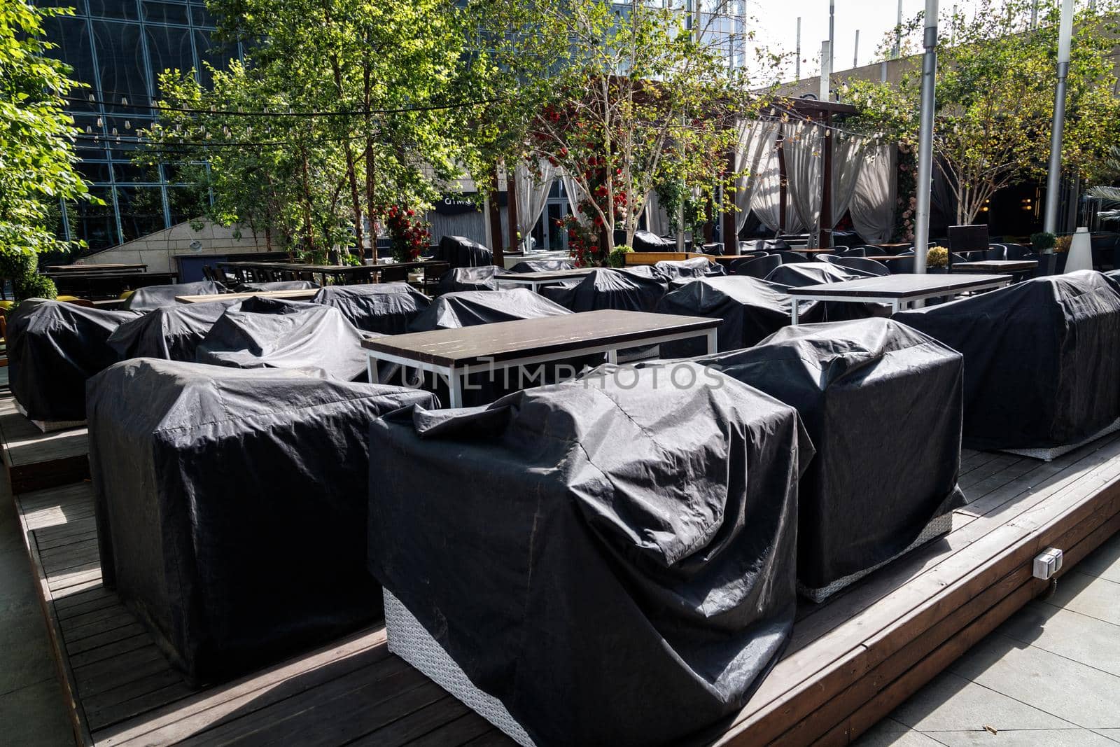 Outdoor cafe with furniture covered with rain covers. Preparing a street cafe for the season. Almaty, Kazakhstan - September 20, 2021