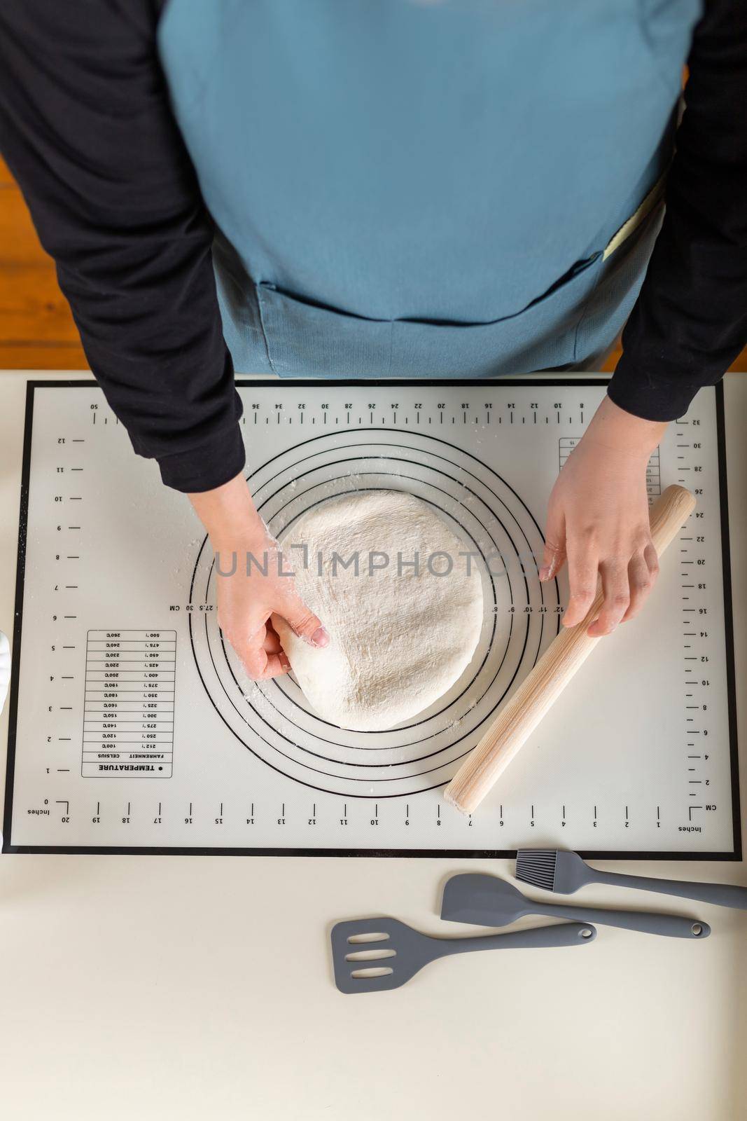 Top view of dough cooking process with kitchen baking mat, vertical copy space.