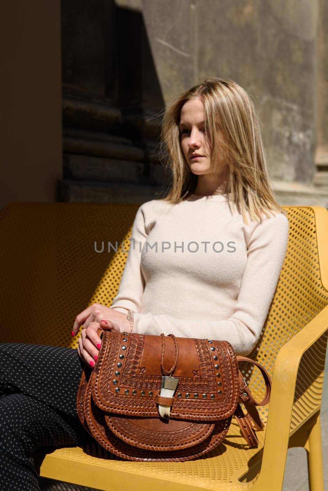 woman with small brown leather bag with a carved pattern. selective focus by Ashtray25