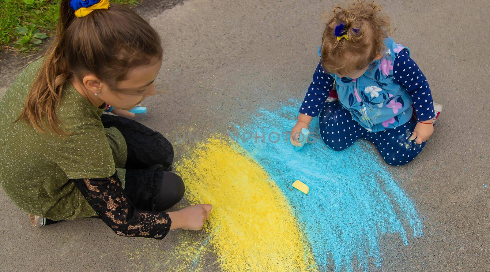 Children draw the Ukrainian flag on the pavement. Selective focus. by yanadjana