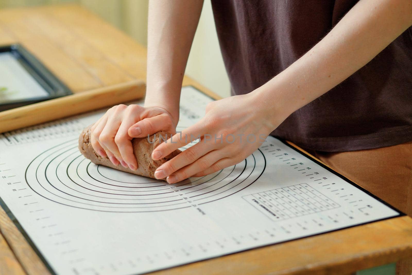 Close-up on female hands that knead the dough for gingerbread cookies on a baking mat.