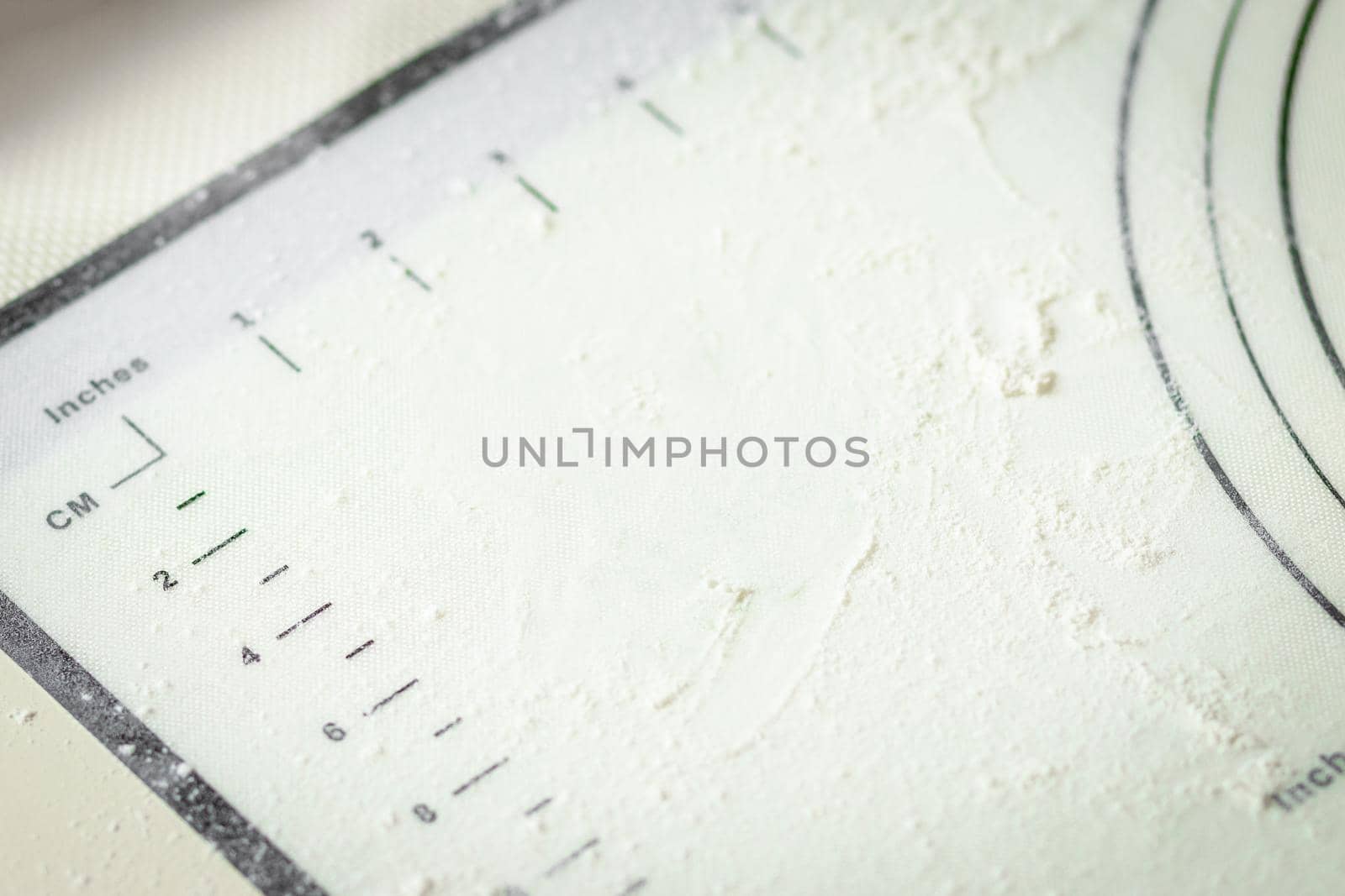 White silicone cooking mat with centimeter and inch markings sprinkled with flour, copy space.