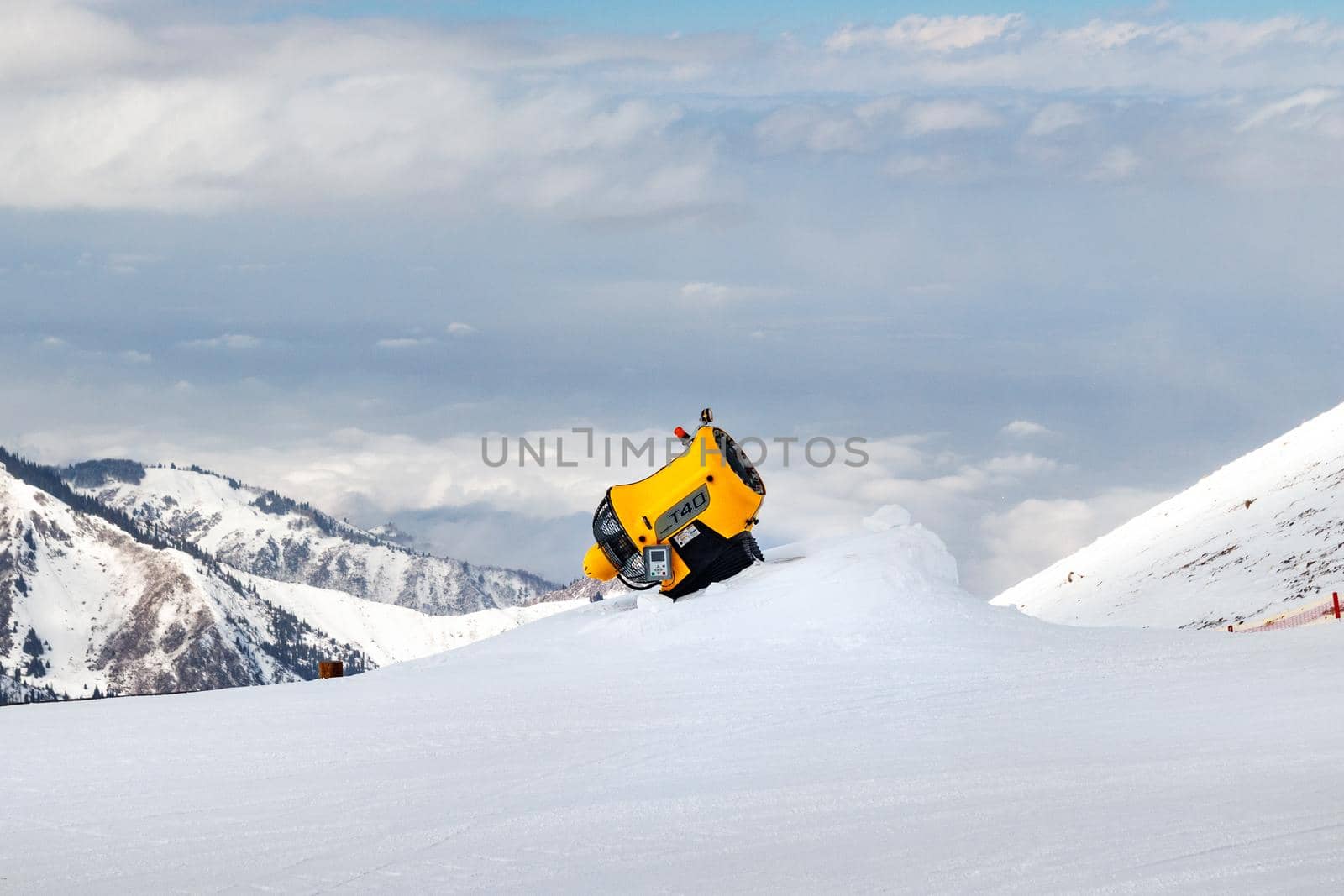 Almaty, Kazakhstan - March 16, 2021: technoalpin t40 Snow cannon against the rocky mountain slope. Snow making machine on ski slopes