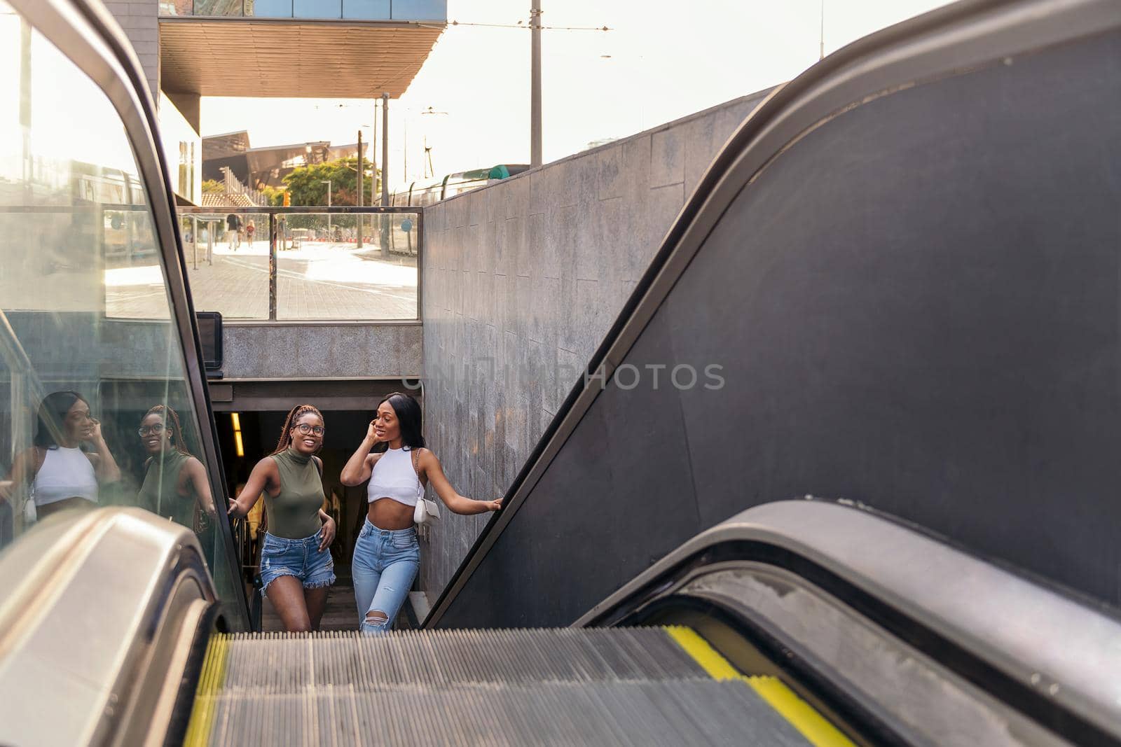 two black girls going up the escalator in the subway, concept of friendship and urban lifestyle