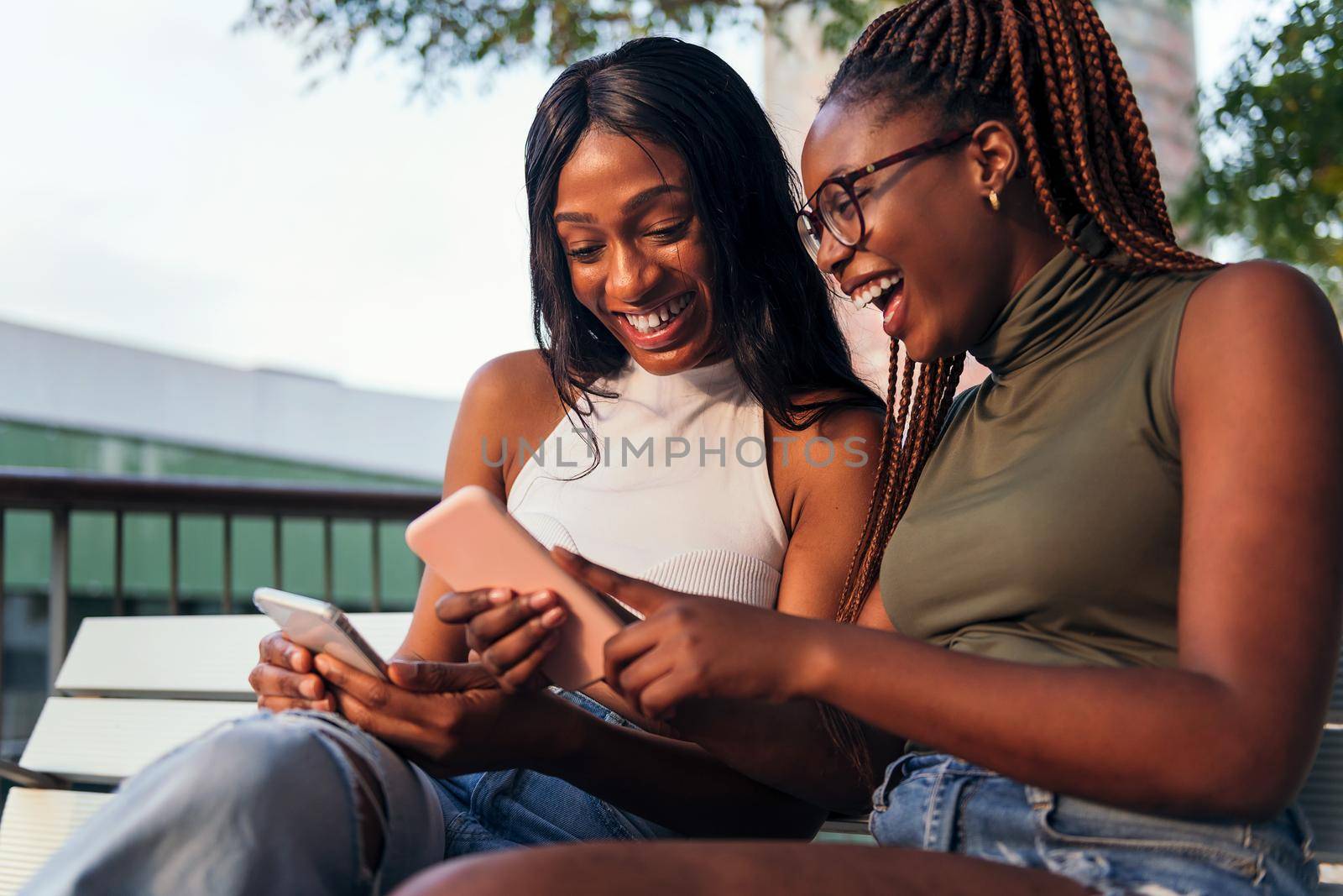 two young women laughing while looking phones by raulmelldo