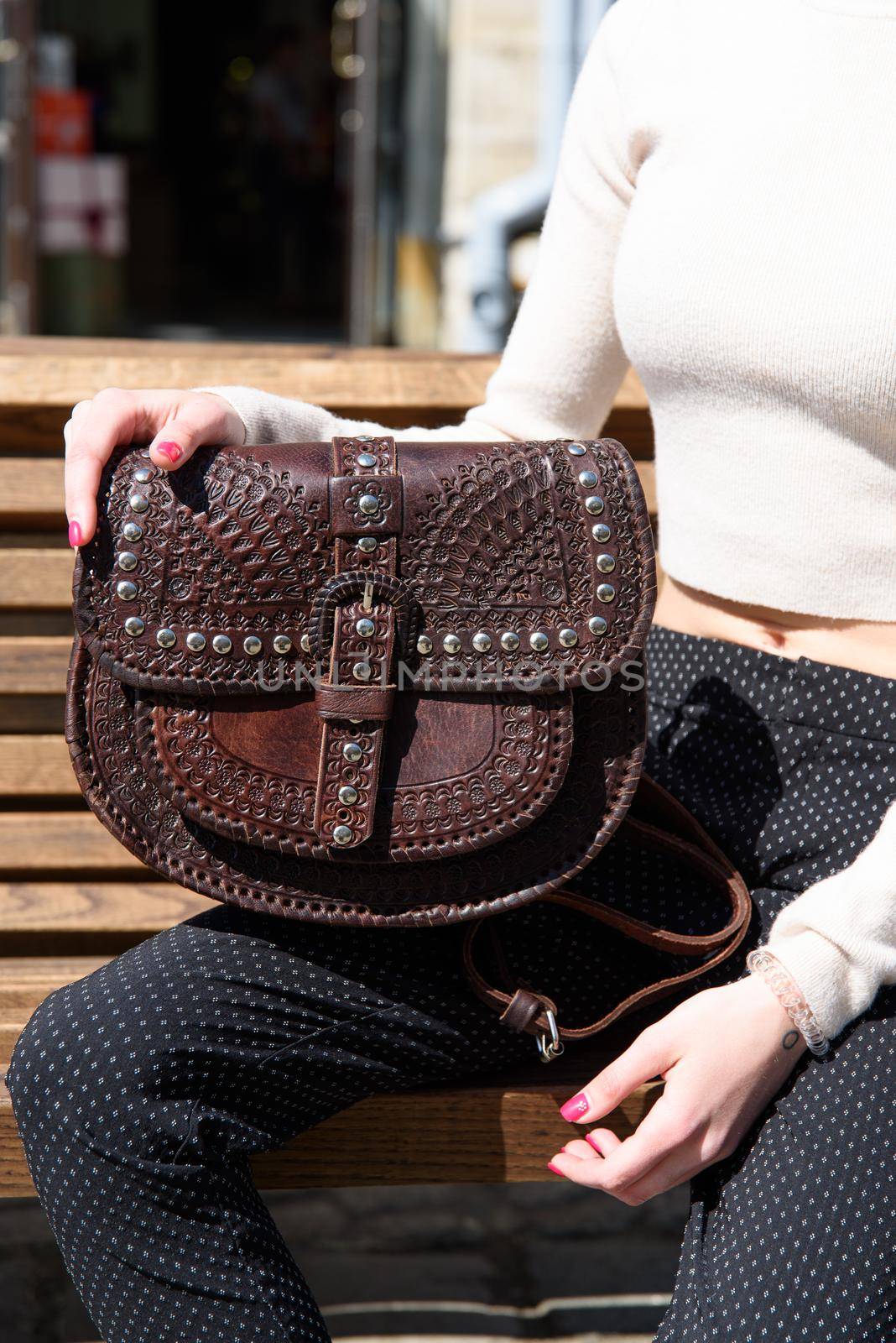 small brown women's leather bag with a carved pattern. street photo