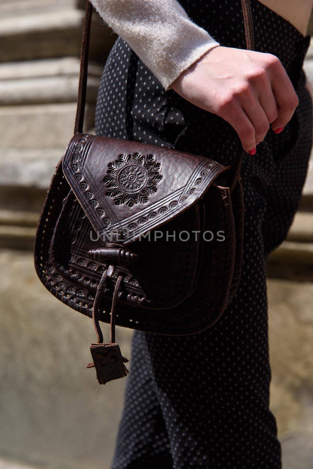 small brown women's leather bag with a carved pattern. street photo