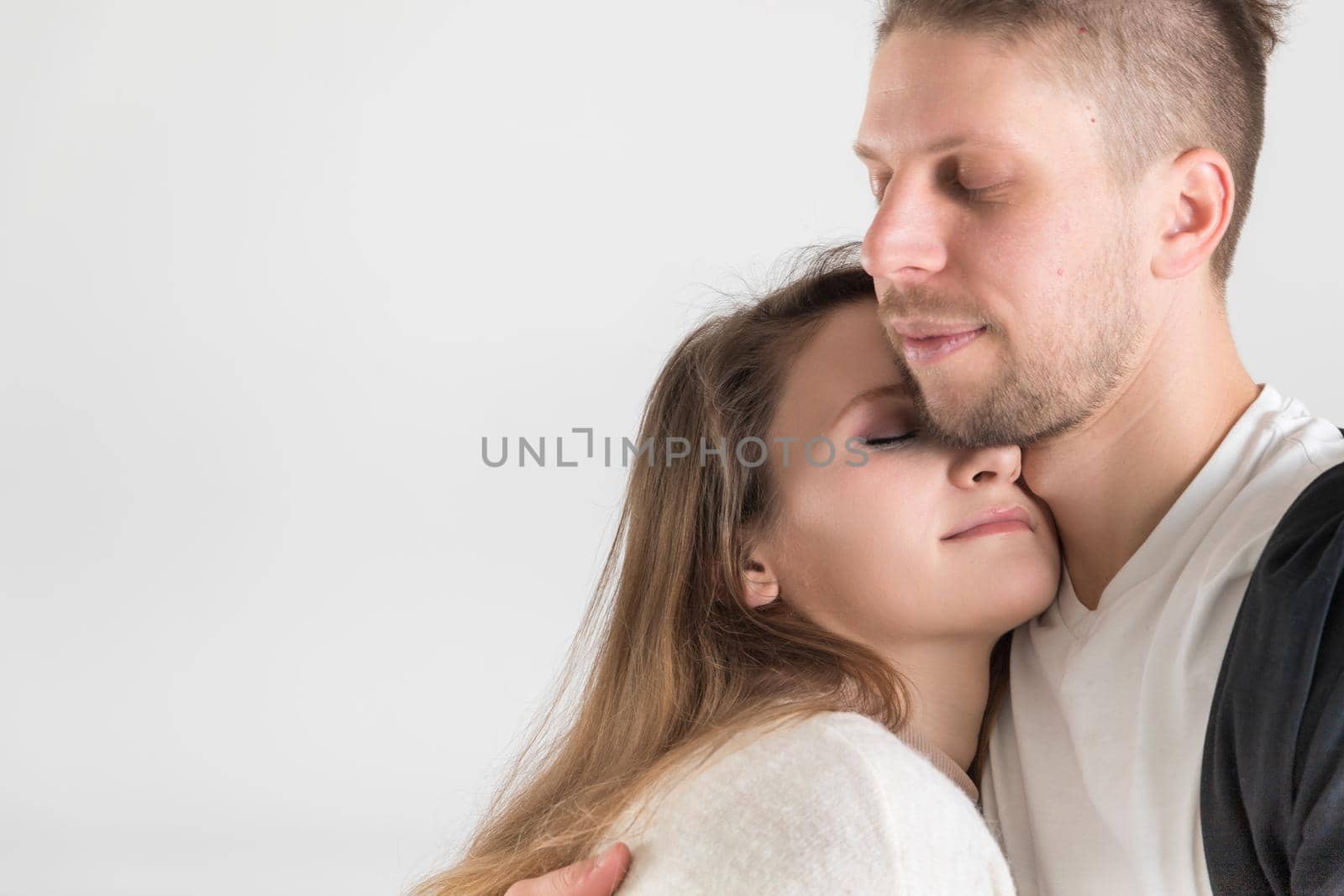 Tender portrait of a young caucasian couple of lovers on a white background with copy space.