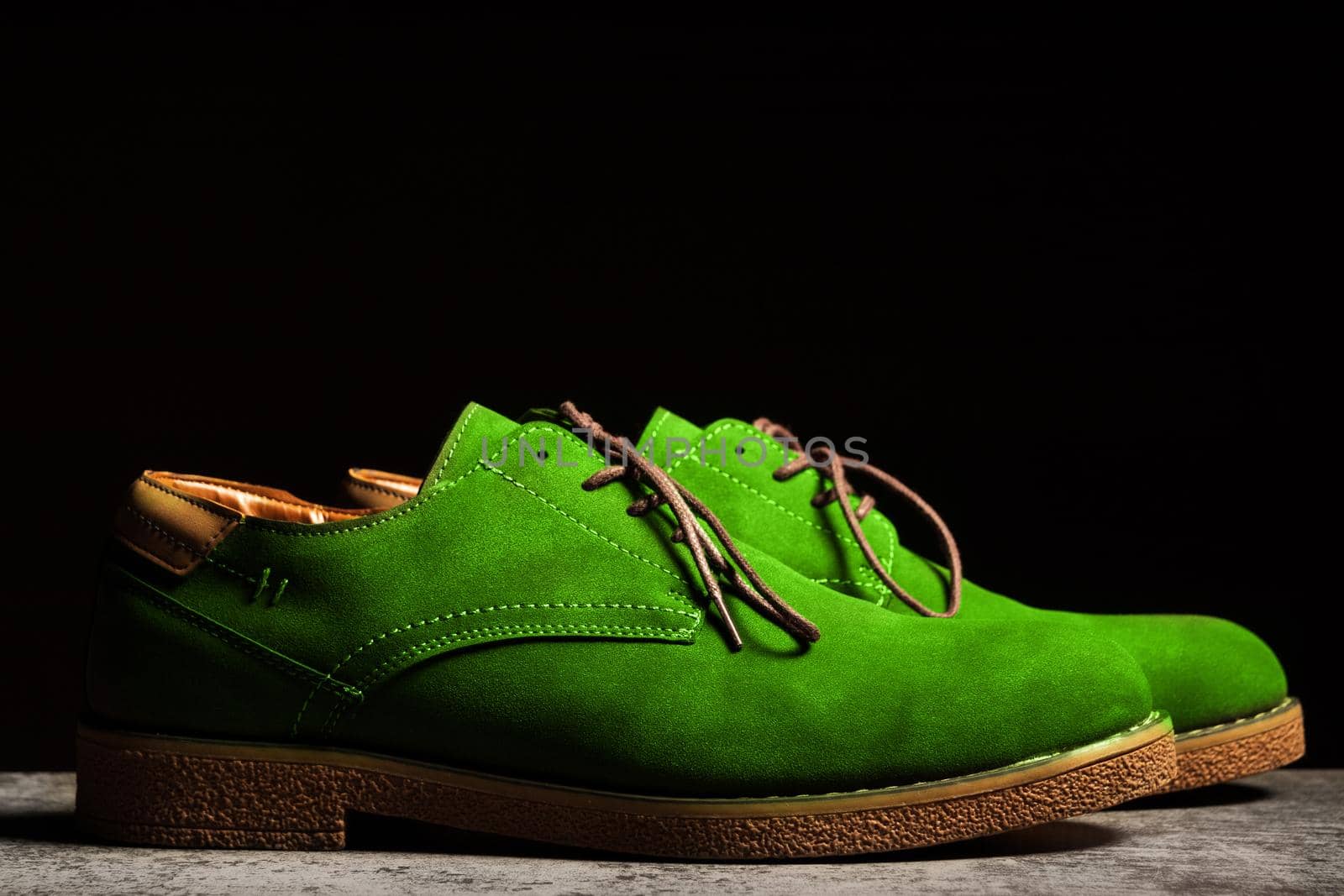Side view of green concert shoes with laces on a black background.