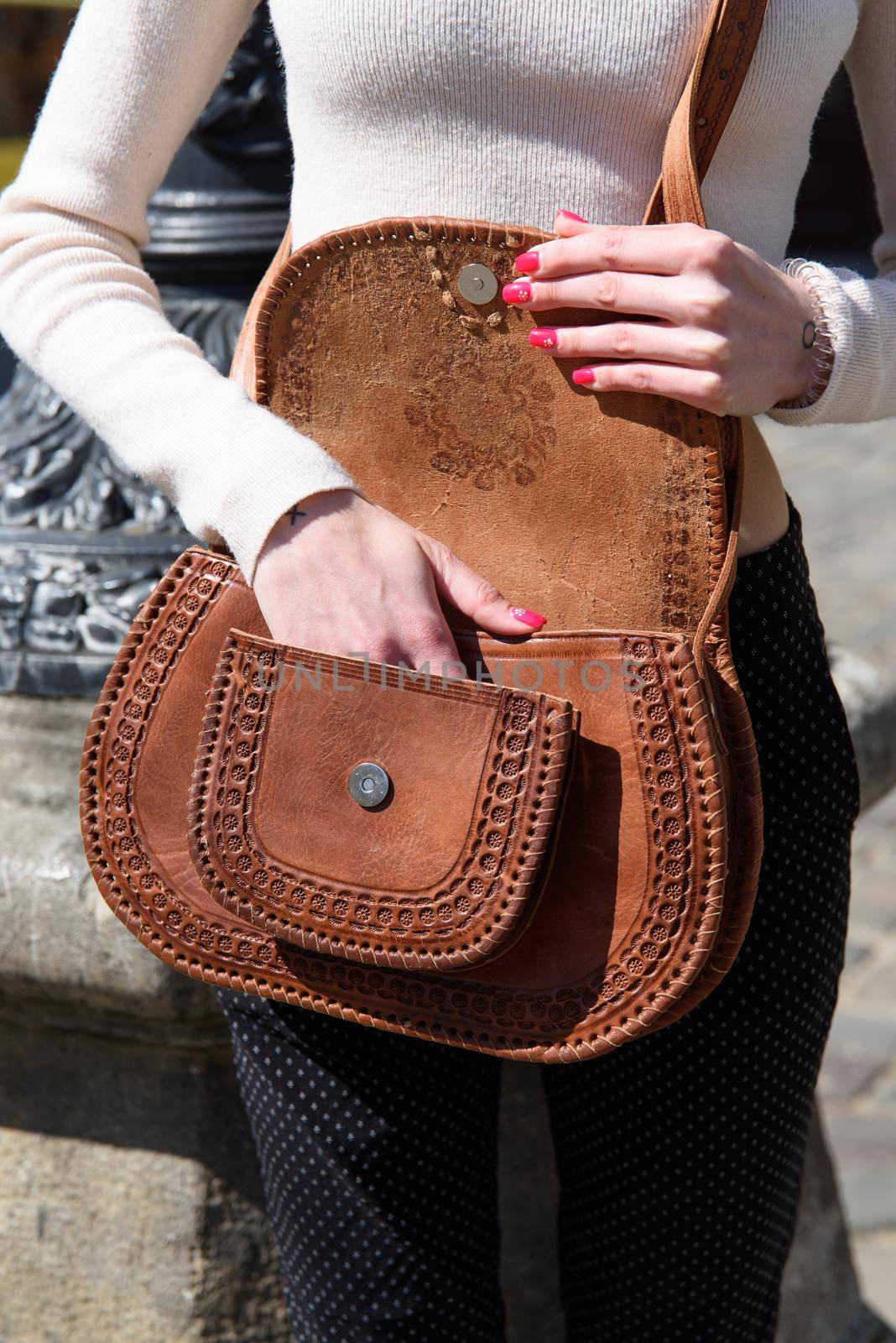 open small brown women's leather bag with a carved pattern. selective focus by Ashtray25