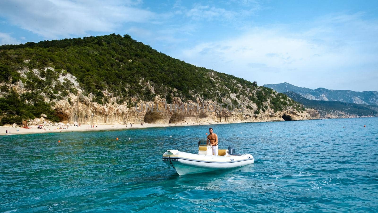 Golfo di Orosei Sardina, Men on the beach chilling in speed boat Sardinia Italy, young guy on vacation Sardinia Italy, a man playing in the ocean with crystal clear blue water