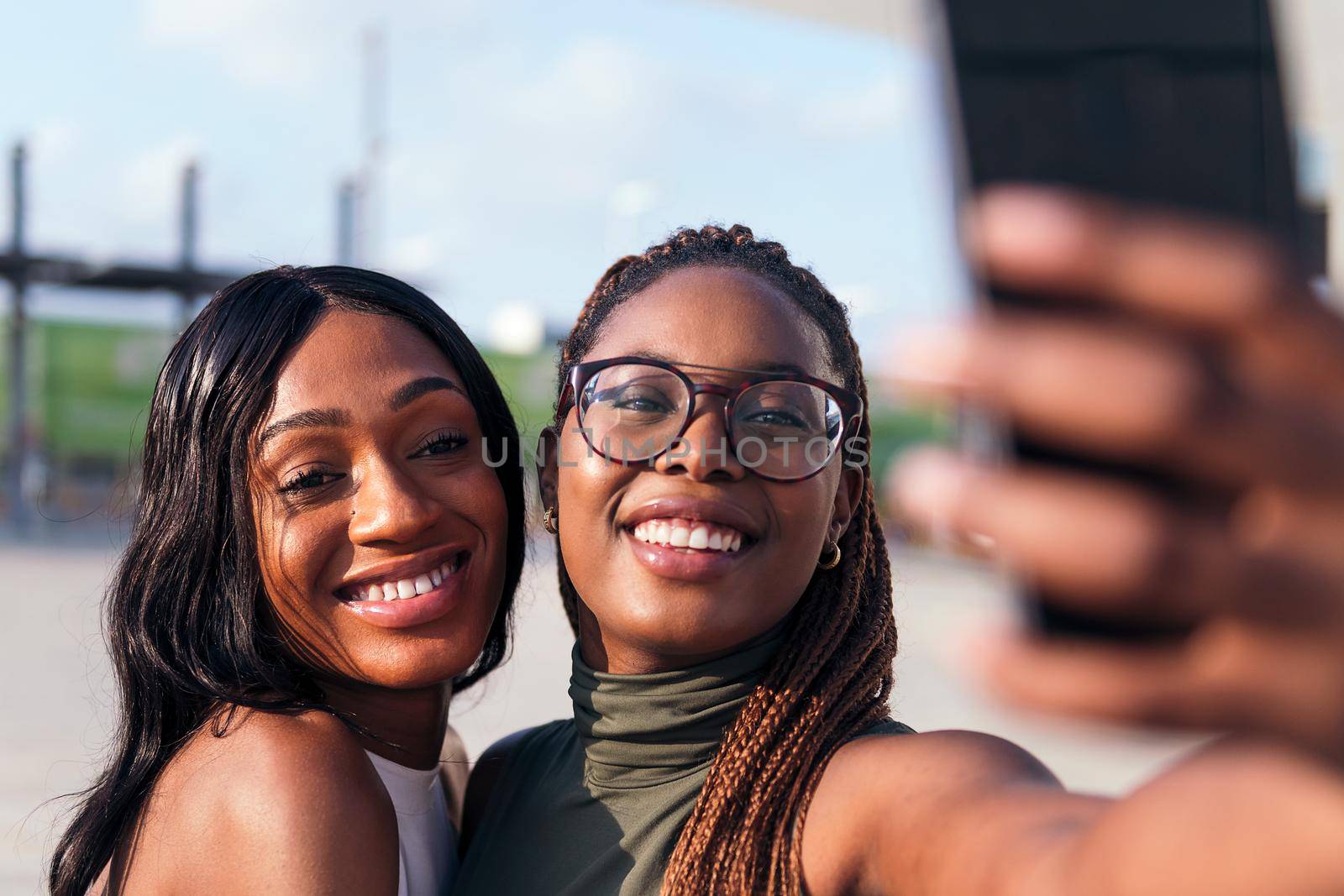 two young african friends smiling happy to take a selfie photo with a cell phone, concept of youth and friendship