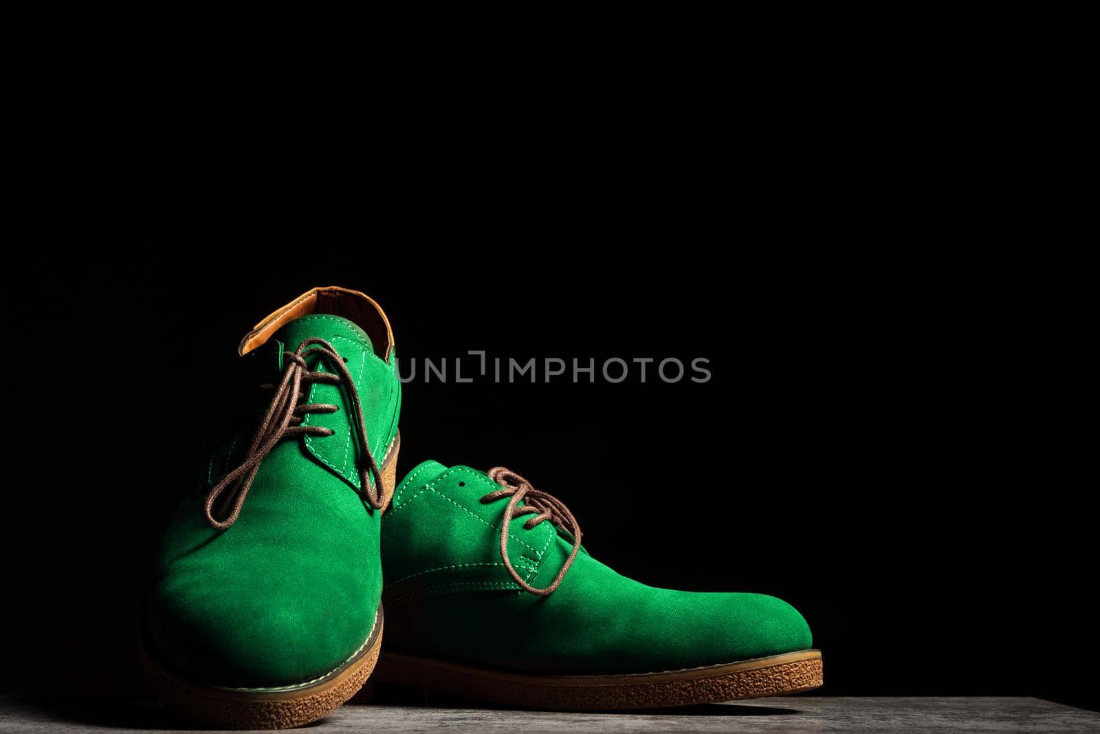 Concert green shoes with laces on a black background with copy space.