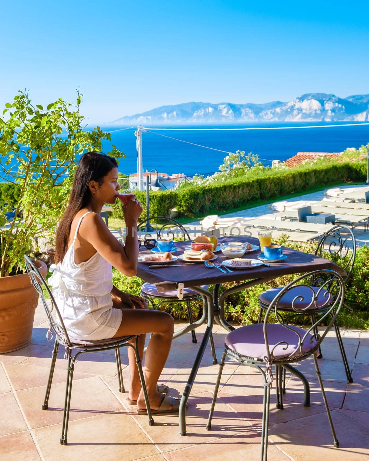 Golfo di Orosei Sardina, a woman having breakfast in the morning with a view of the ocean in Sardinia Italy