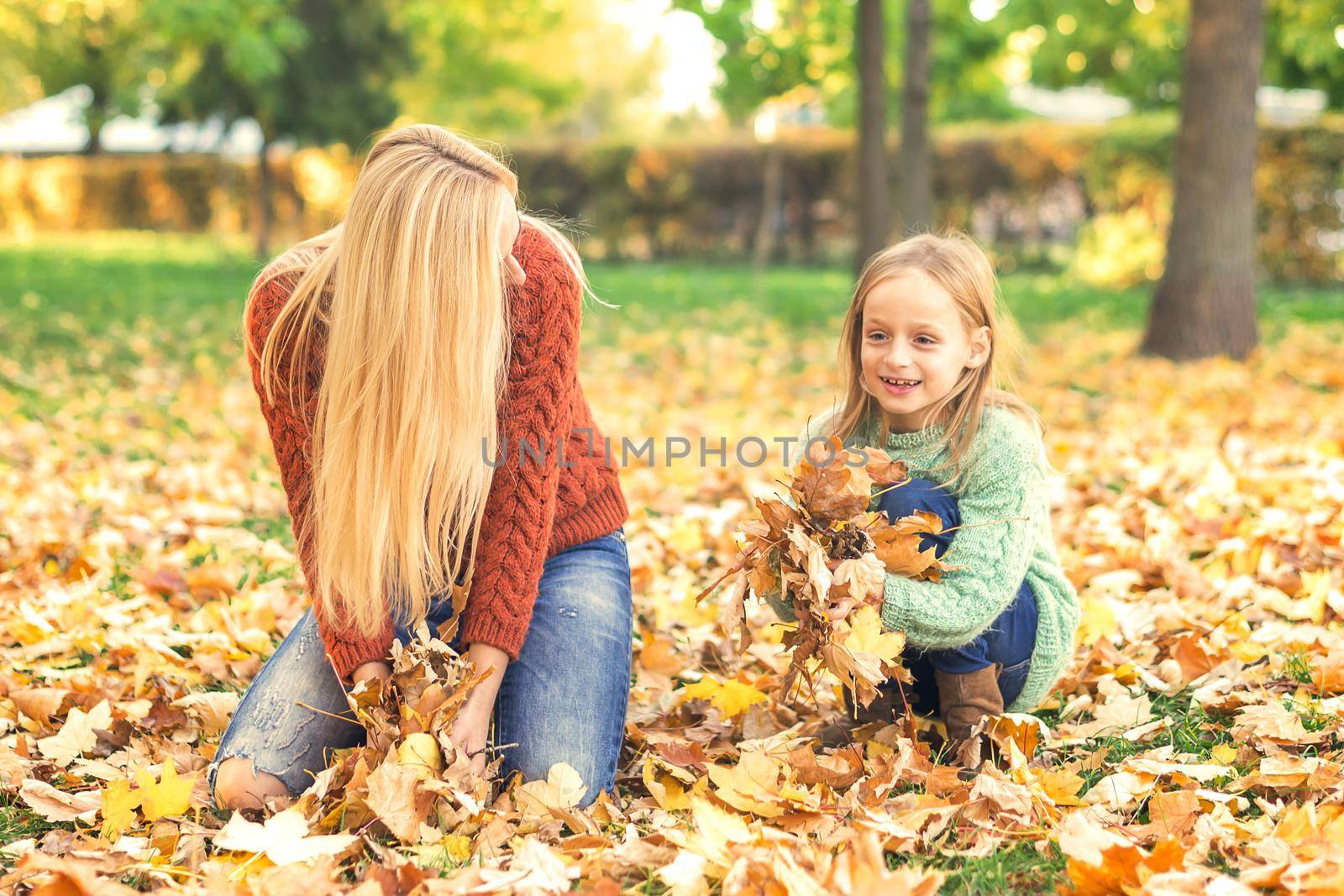 Mother and child playing with leaves in autumn by okskukuruza