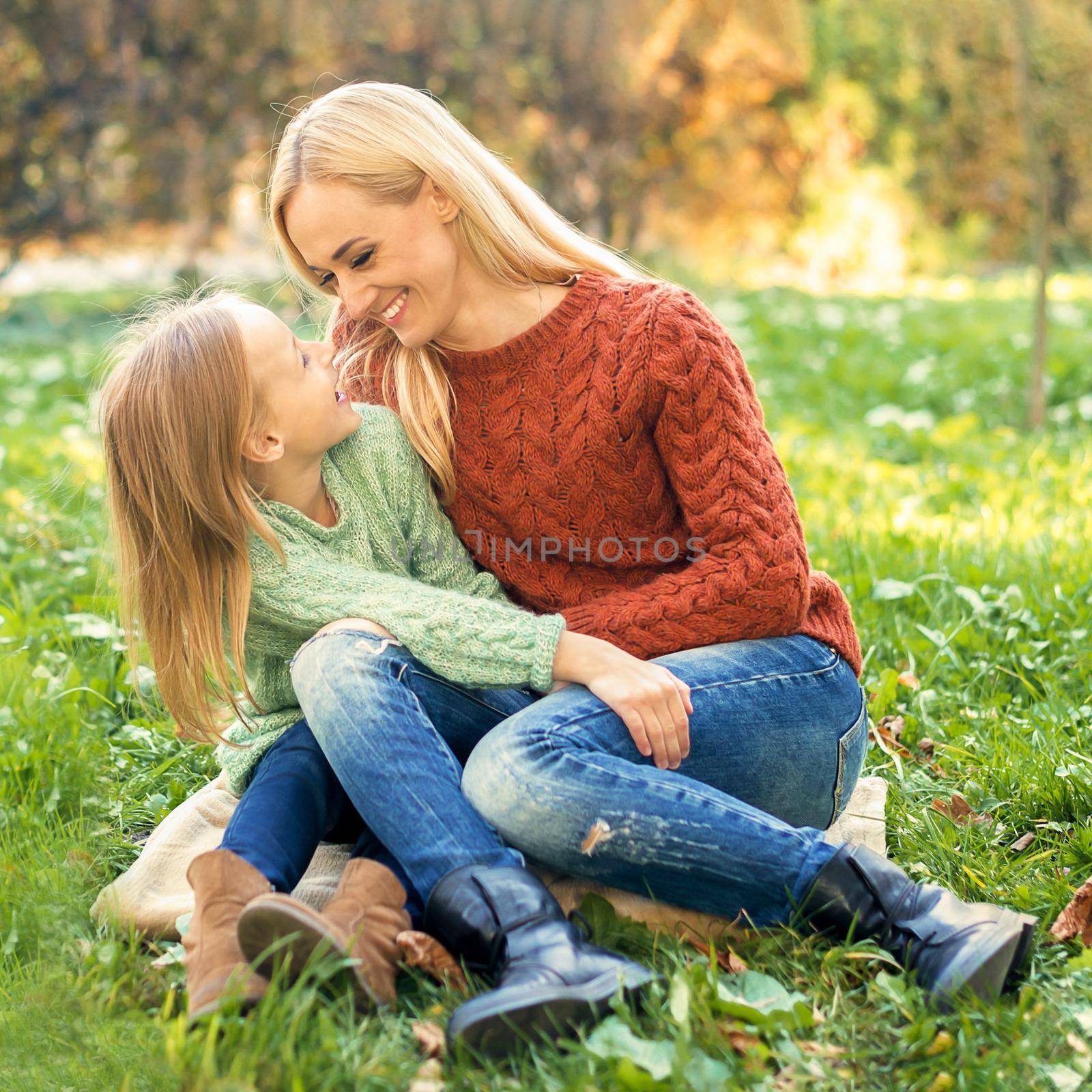 Young mother and little daughter hugging each other outdoors. by okskukuruza