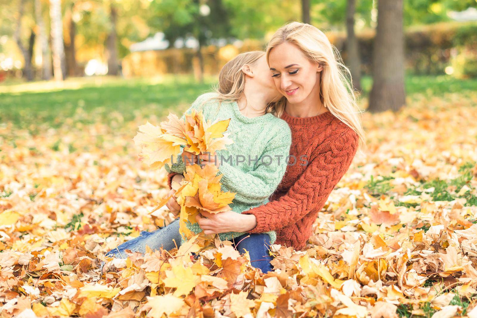 Woman and girl holding autumn yellow leaves by okskukuruza