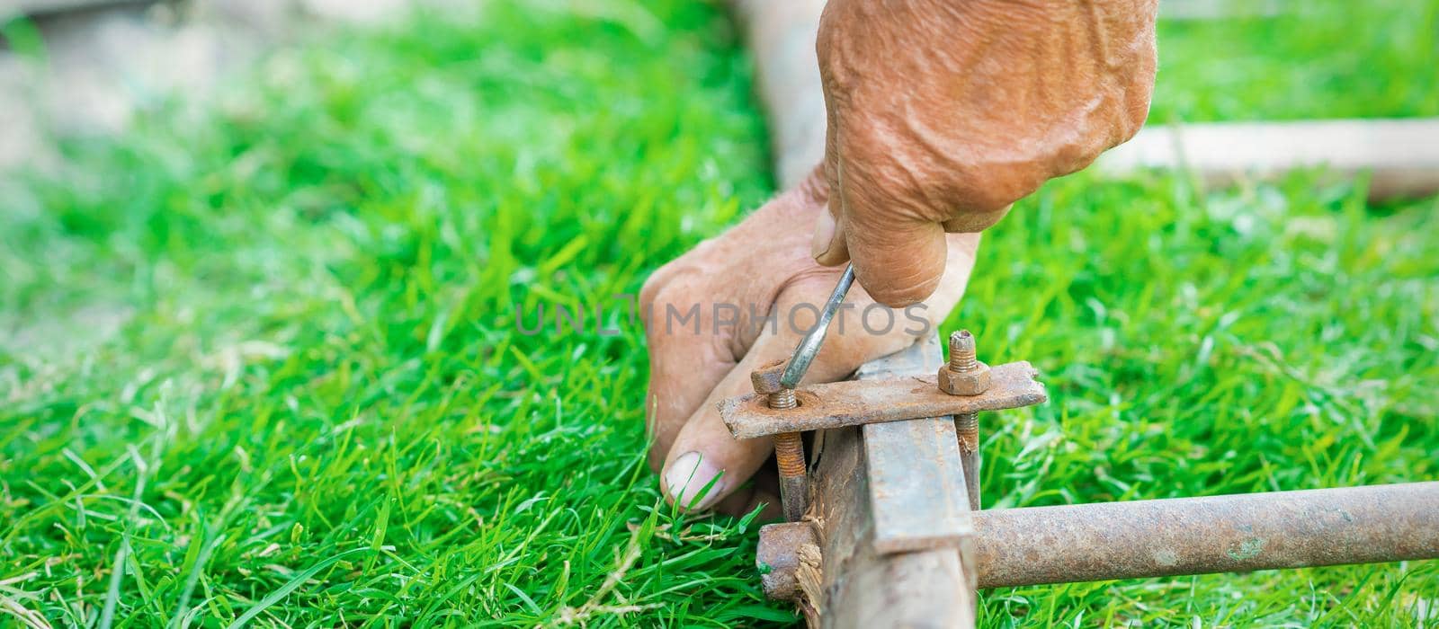 hand of an elderly man twisting the nut with a wrench outdoors. Repair by wrench.