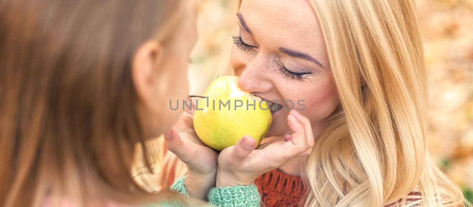 Girl with mother eating apple by okskukuruza