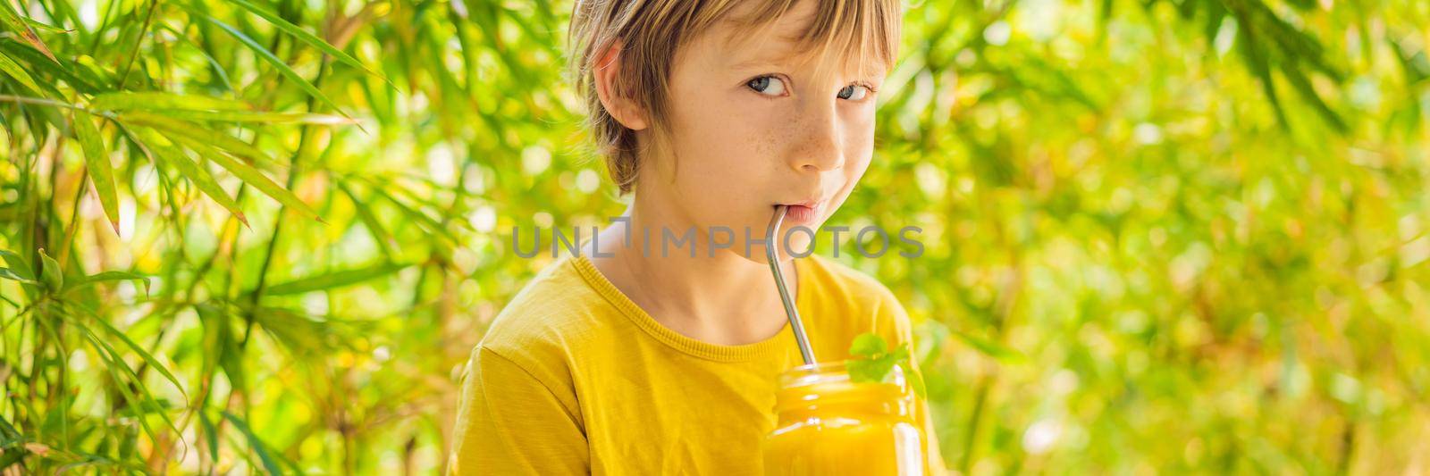 Boy drinking juicy smoothie from mango in glass mason jar. Healthy life concept, copy space. BANNER, LONG FORMAT