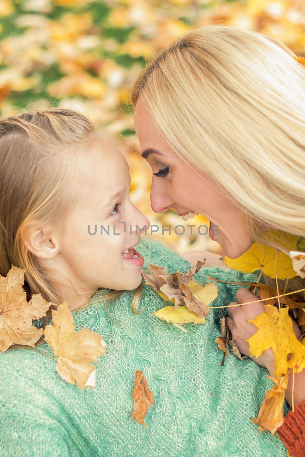 Beautiful young caucasian mother playing with her little child in the autumn park