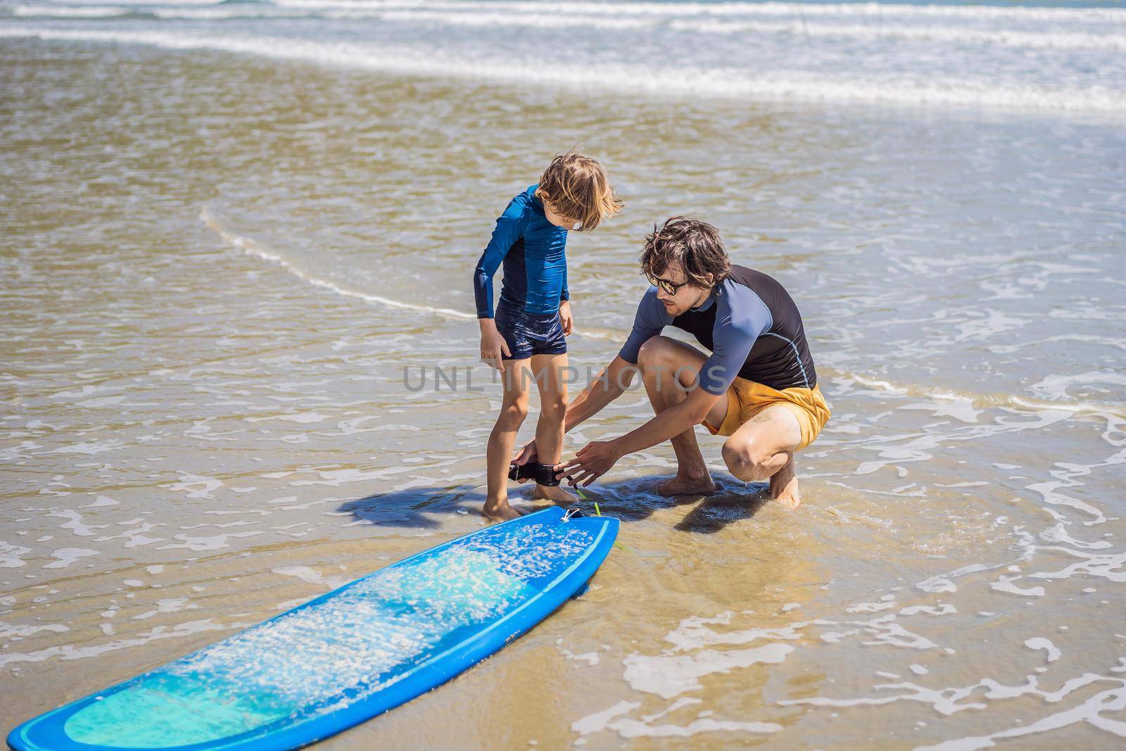 Father or instructor teaching his son how to surf in the sea on vacation or holiday. Travel and sports with children concept. Surfing lesson for kids.