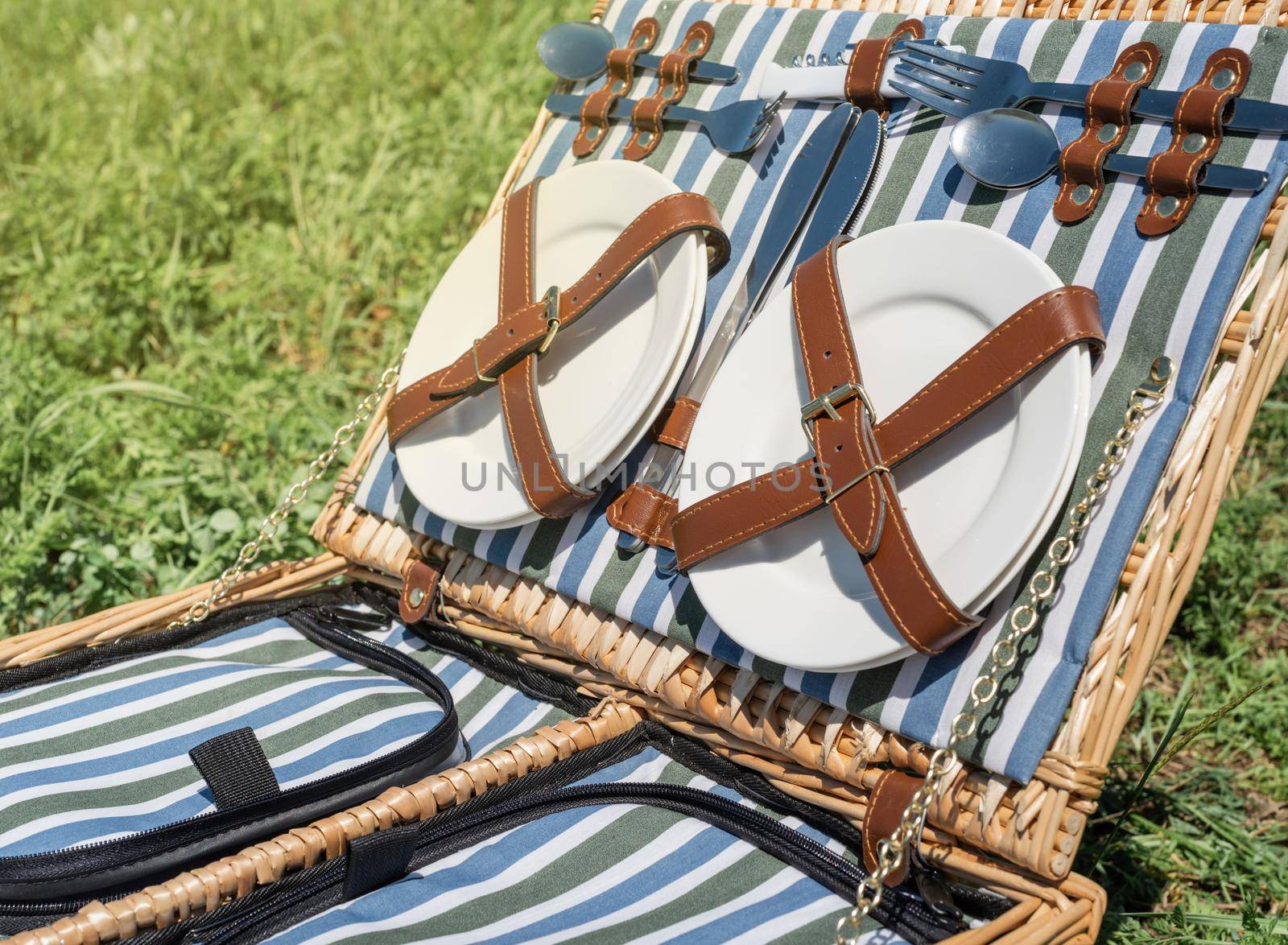 Closeup of picnic basket with drinks and food on the grass by Desperada