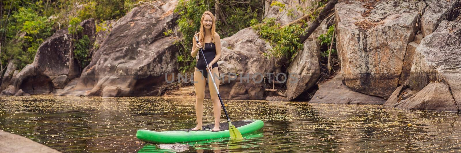 SUP Stand up paddle board woman paddle boarding on lake standing happy on paddleboard on blue water.Action Shot of Young Woman on Paddle Board. BANNER, LONG FORMAT