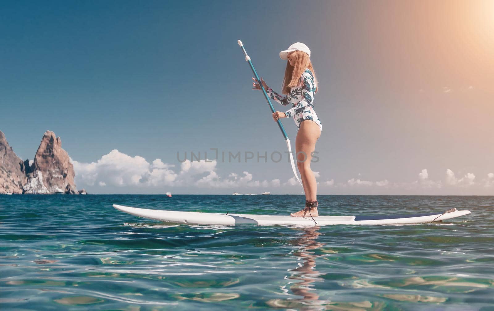 SUP Stand up paddle board. Young woman sailing on beautiful calm sea with crystal clear water. The concept of an summer holidays vacation travel, relax, active and healthy life in harmony with nature