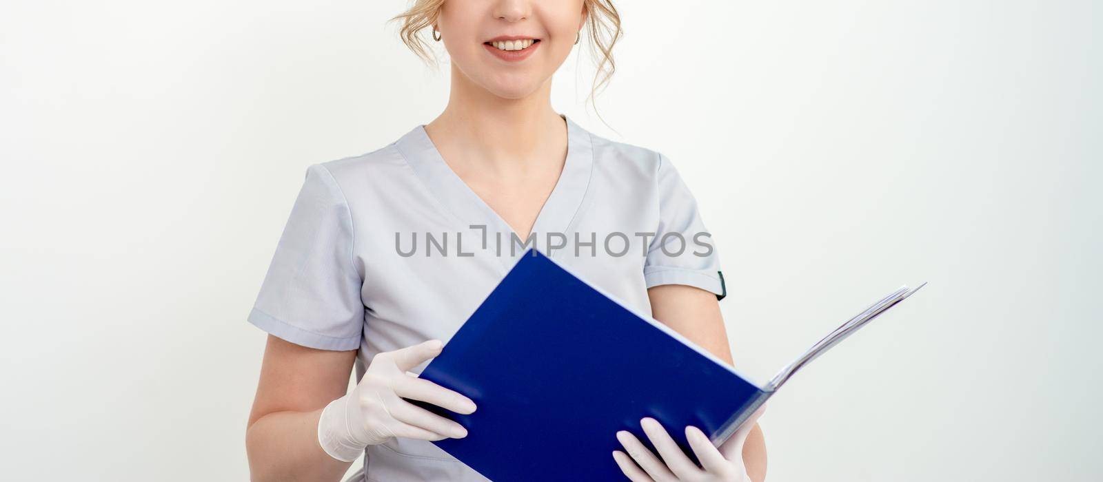 Portrait of nice young caucasian woman in gloves holding blue folder looking at camera on white background