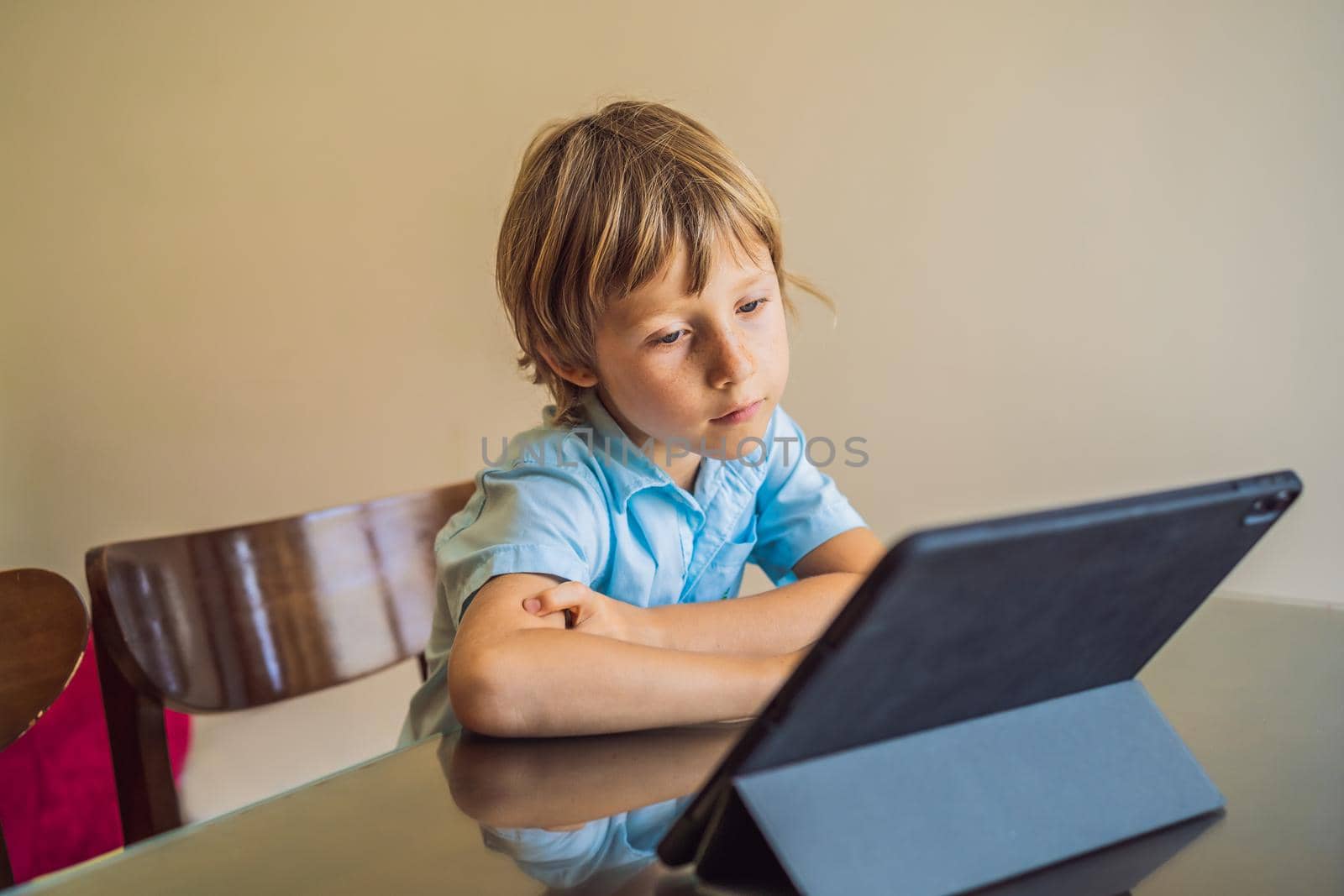 Boy studying online at home using tablet. Studying during quarantine. Global pandemic covid19 virus.