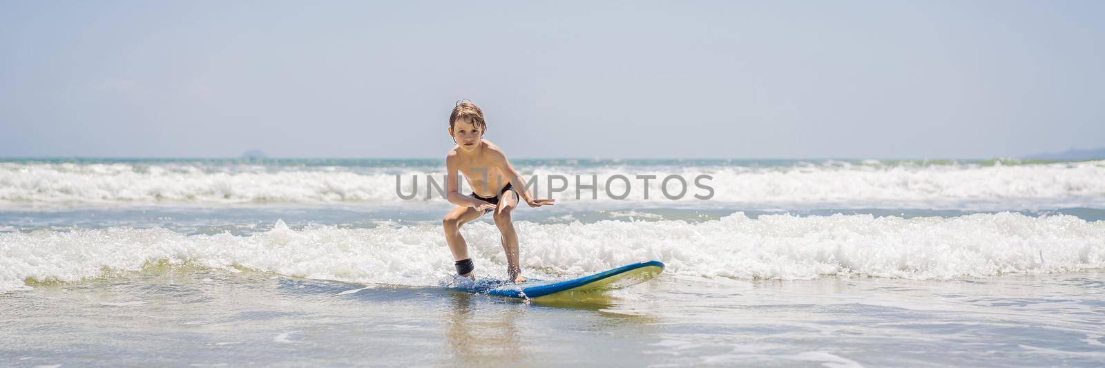 Healthy young boy learning to surf in the sea or ocean. BANNER, LONG FORMAT
