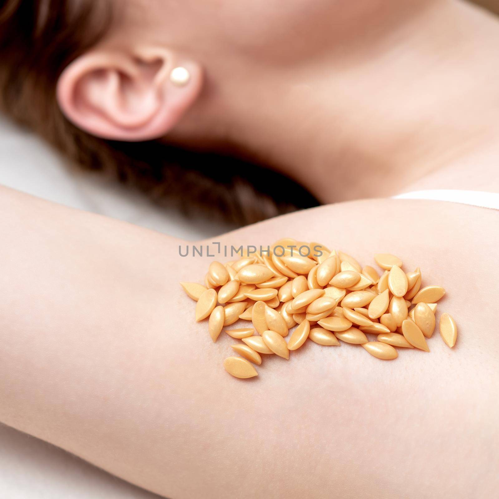 Wax orange beans on armpit of young caucasian woman. Depilation concept