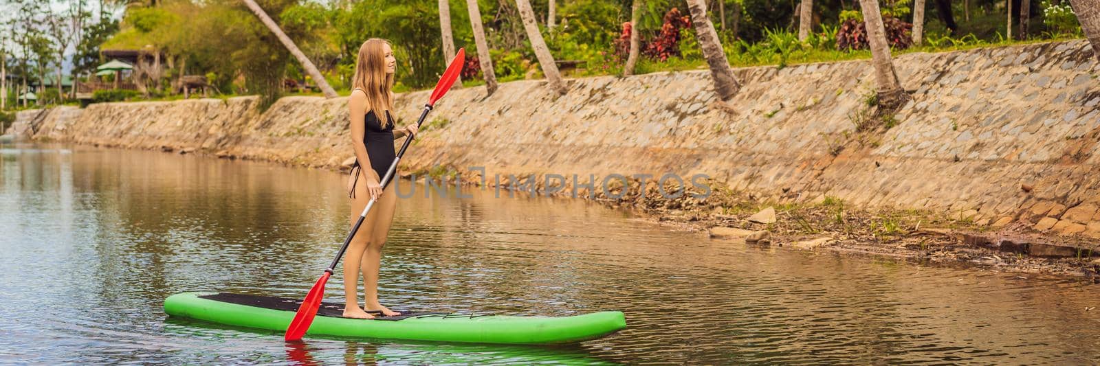 SUP Stand up paddle board woman paddle boarding on lake standing happy on paddleboard on blue water. Action Shot of Young Woman on Paddle Board BANNER, LONG FORMAT by galitskaya