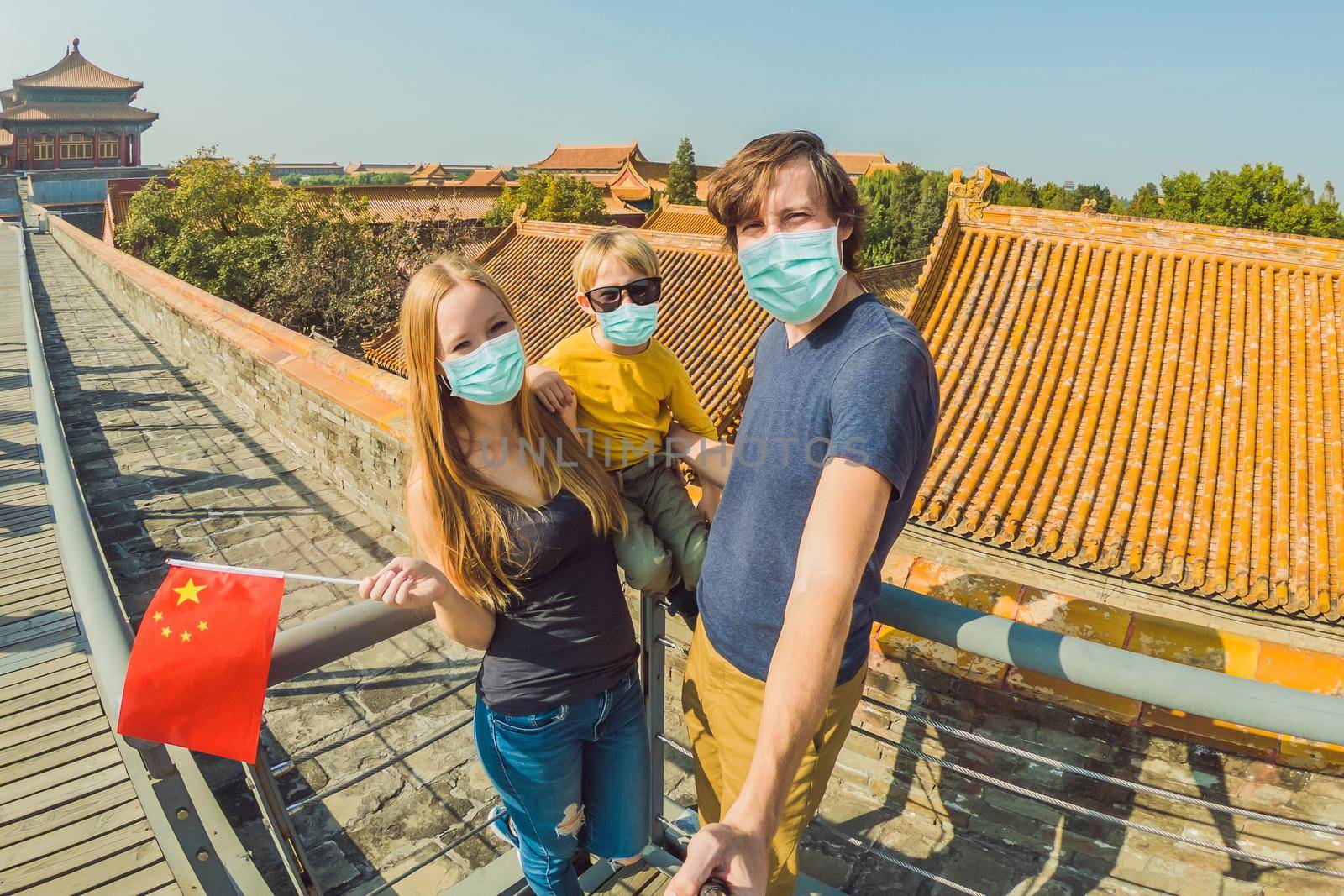 Enjoying vacation in China. Happy family in medical mask with national chinese flag in Forbidden City. Travel to China with kids concept. Tourists fear the 2019-ncov virus. Medical masked tourists.
