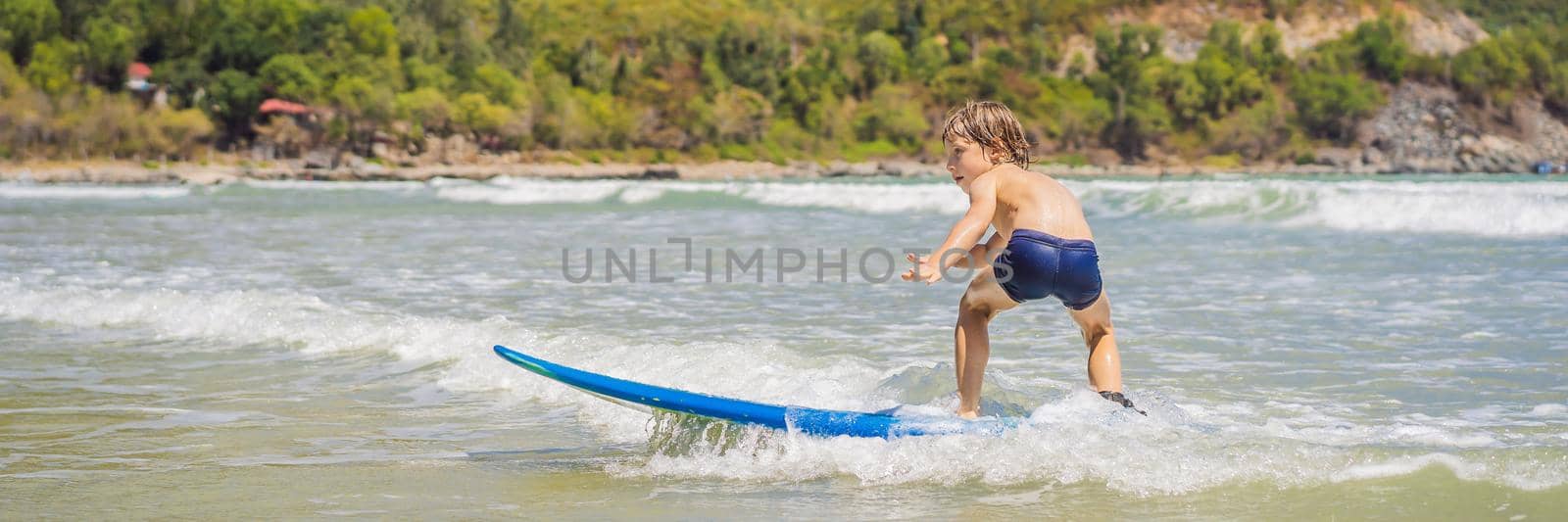 Healthy young boy learning to surf in the sea or ocean BANNER, LONG FORMAT by galitskaya