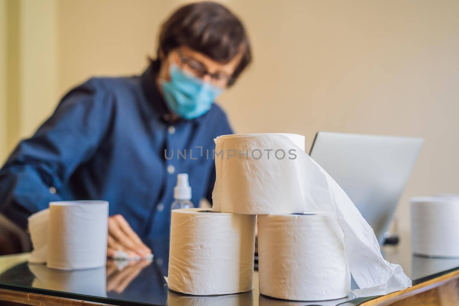 Coronavirus. Man working from home wearing protective mask. quarantine for coronavirus wearing protective mask. Working from home. Cleaning with sanitizer gel. Bought a lot of toilet paper.