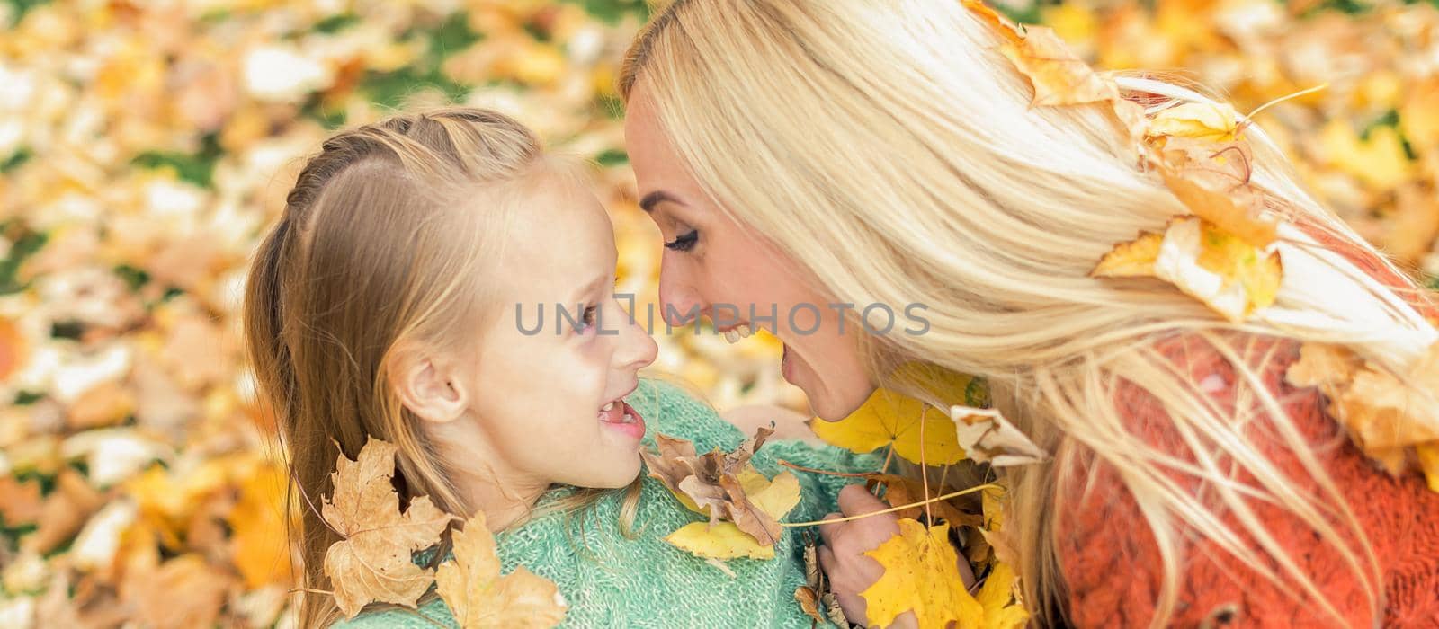 Beautiful young caucasian mother playing with her little child in the autumn park