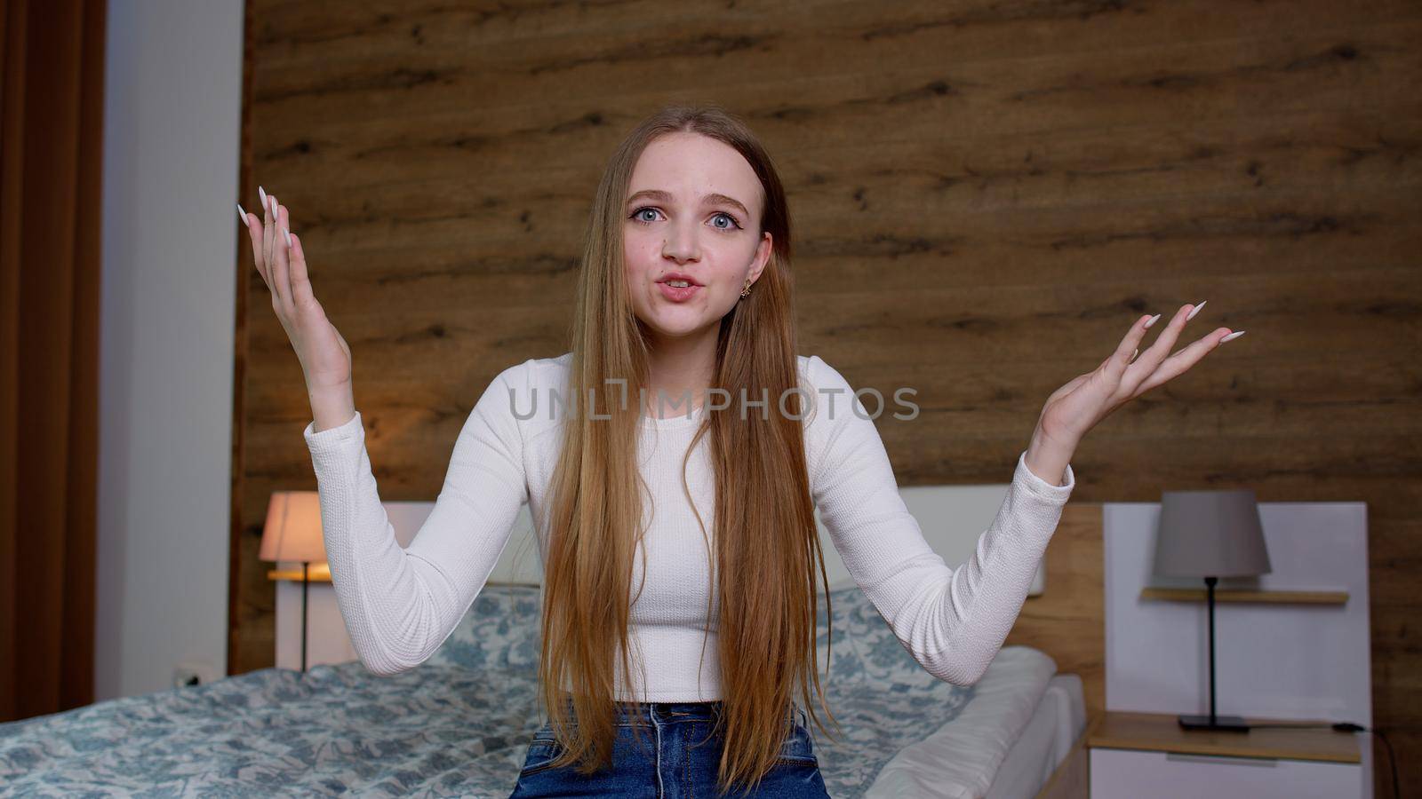Angry irritated young business female woman spreading hands screaming swearing, dressed in white blouse, posing isolated at home bedroom background. People displeased emotions, lifestyle concept