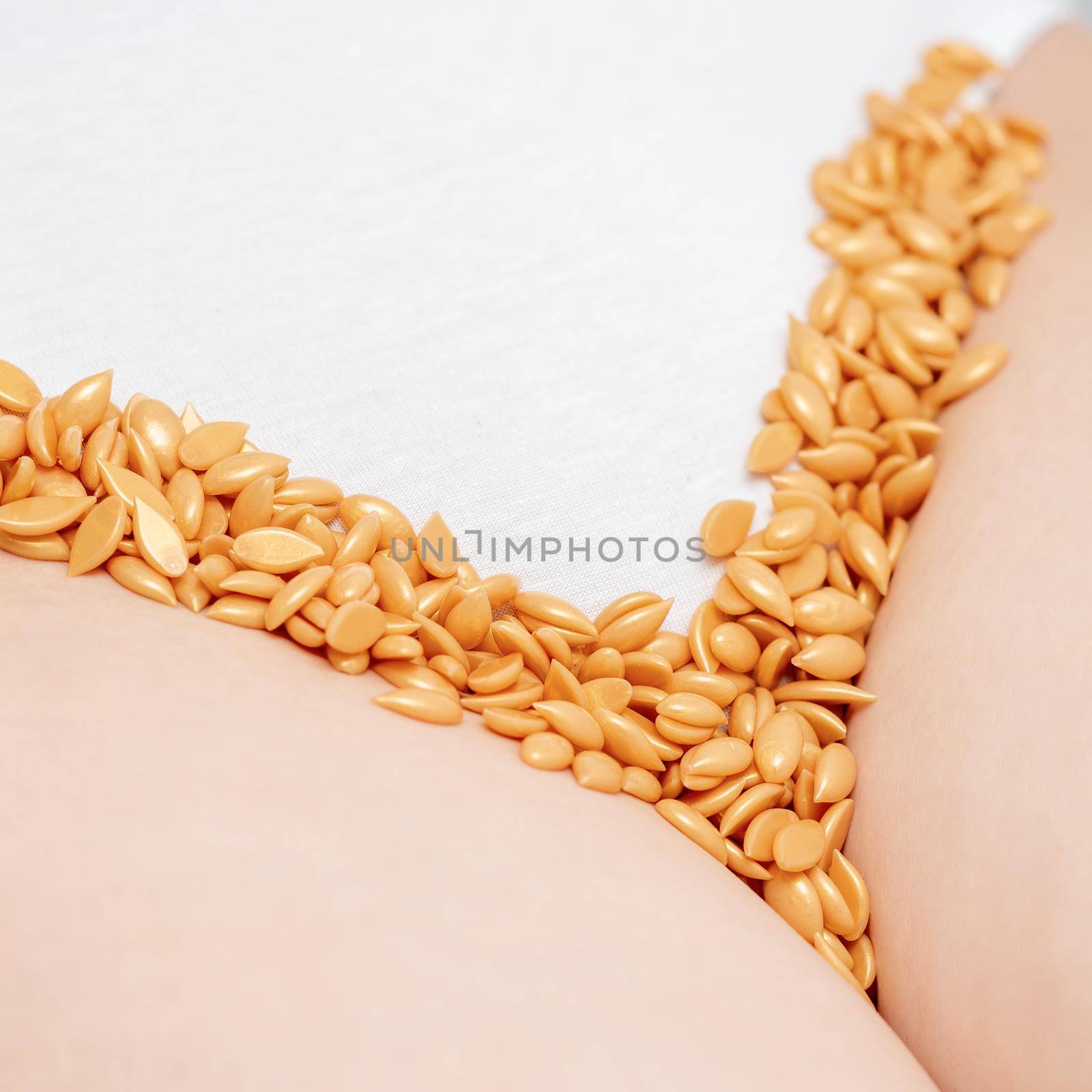Close up of wax beans or seeds lying in row on bikini zone of young woman