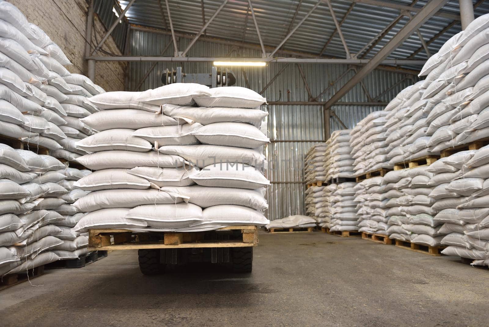 White stacked sacks of wheat in a warehouse.