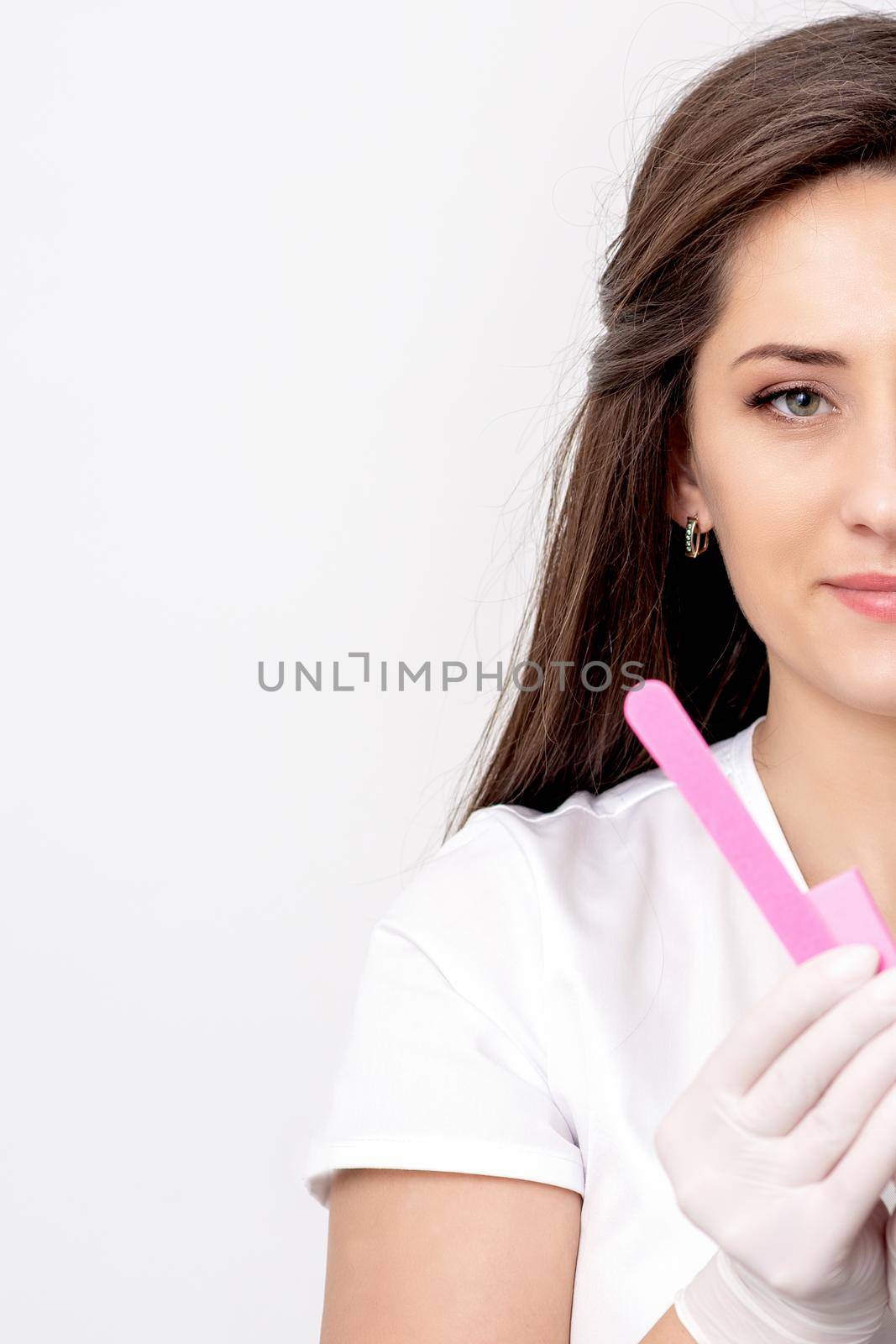 Portrait of beautiful young caucasian woman manicure master holding manicure tools on white background