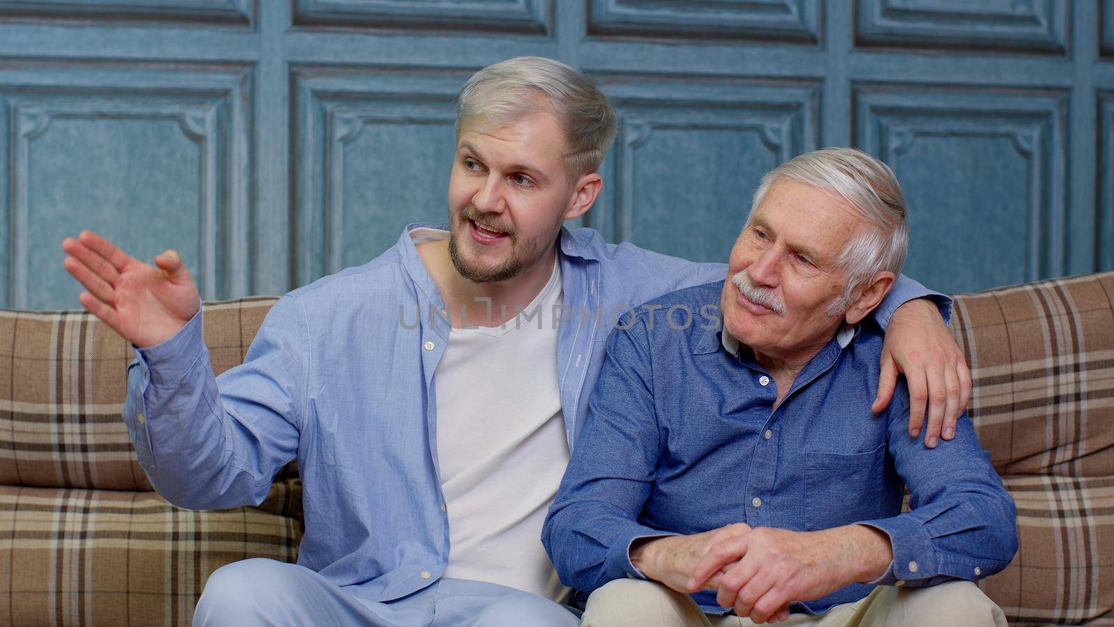 Cheerful bonding loving different male generations family of senior father and adult son or grandson having heart-to-heart conversation. Young man with gray-haired old dad or grandfather. Good friends